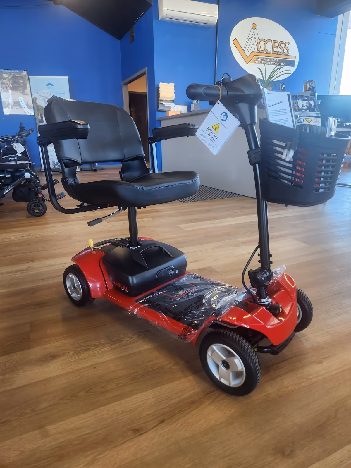 Red mobility scooter displayed inside a blue showroom with the Access logo
