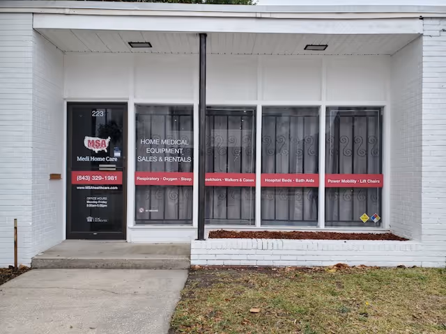 Front view of a white building with large windows displaying medical equipment signage.