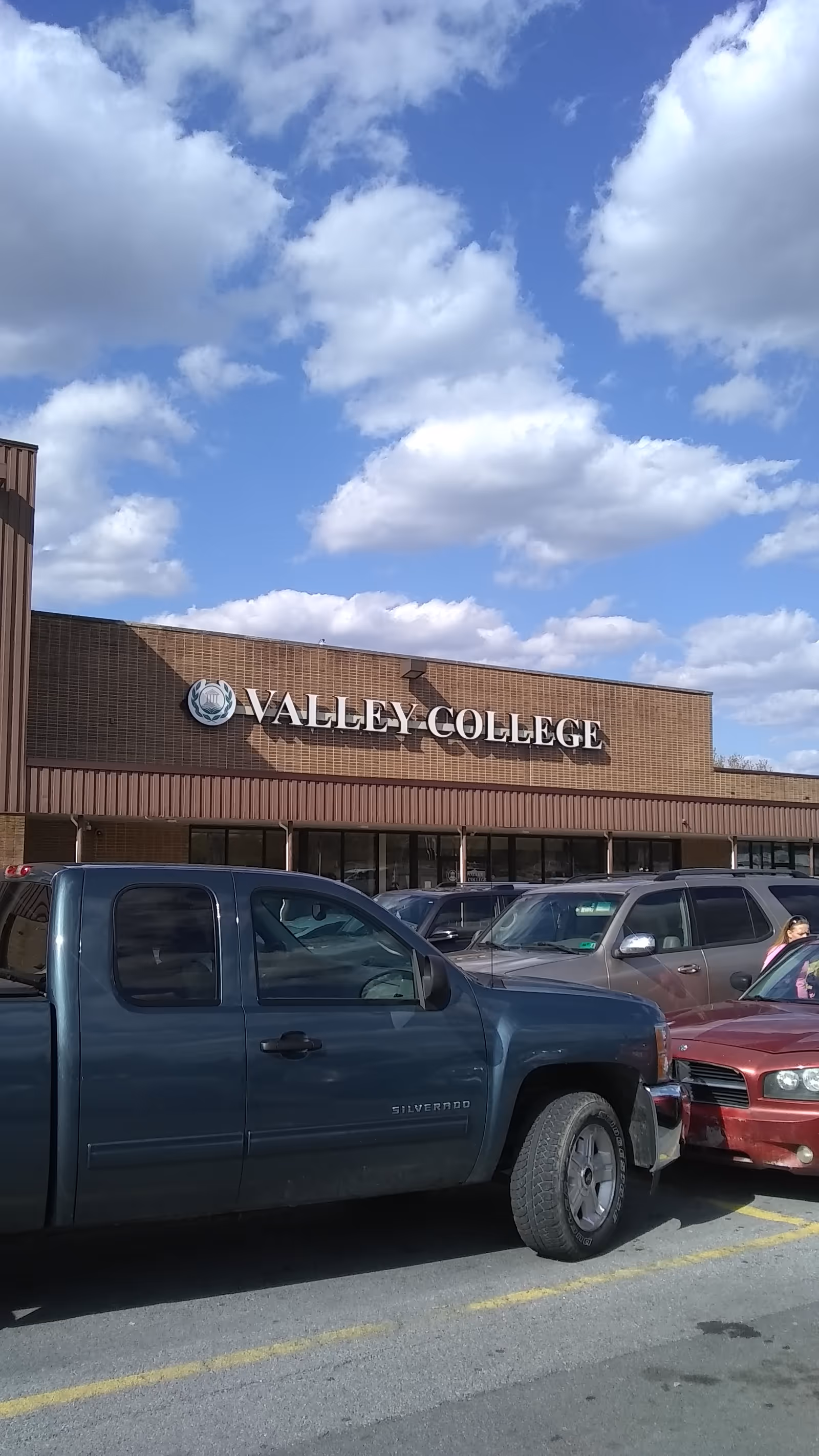 Exterior view of a Valley College building with a parking lot and blue sky.