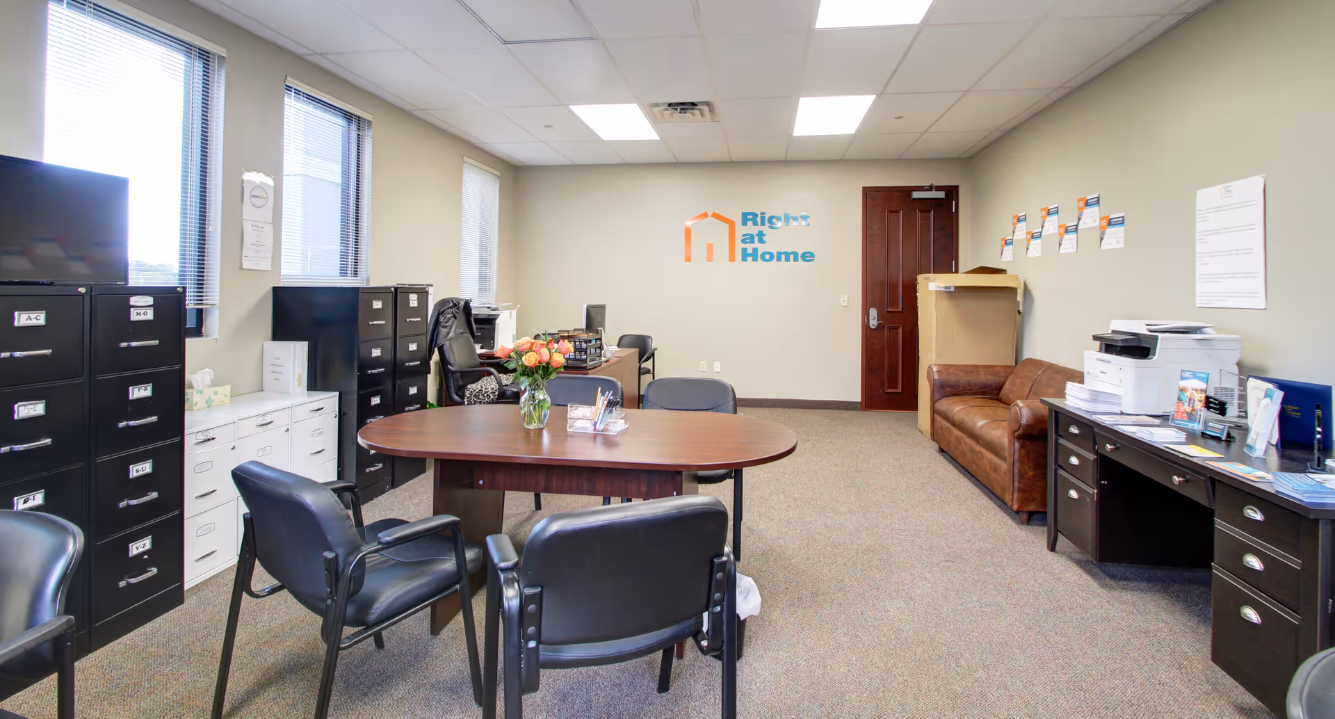 Office-like reception area with round table, chairs, filing cabinets, and a Right at Home logo.