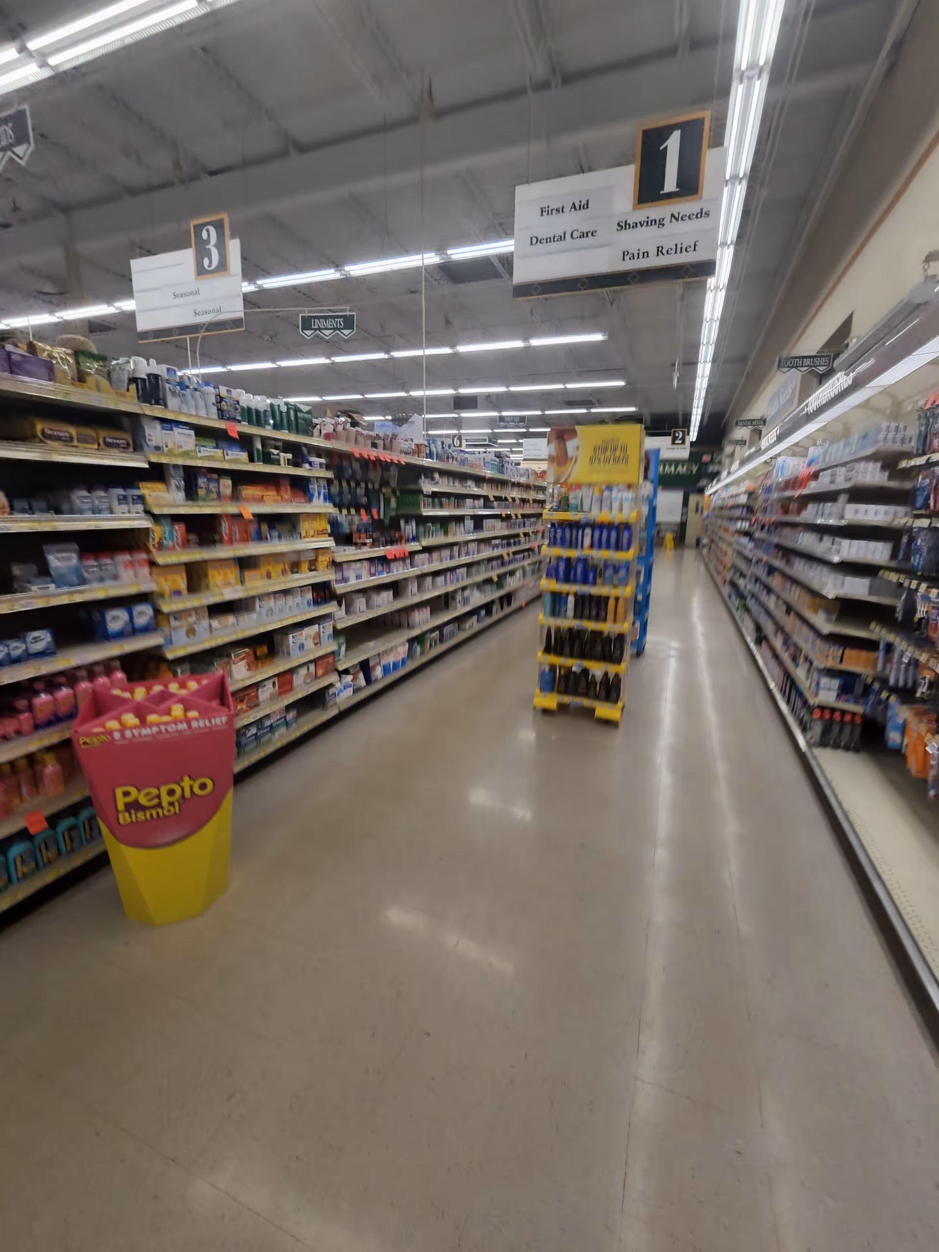 Wide aisle in a Discount Drug Mart store with tall shelves and overhead signs