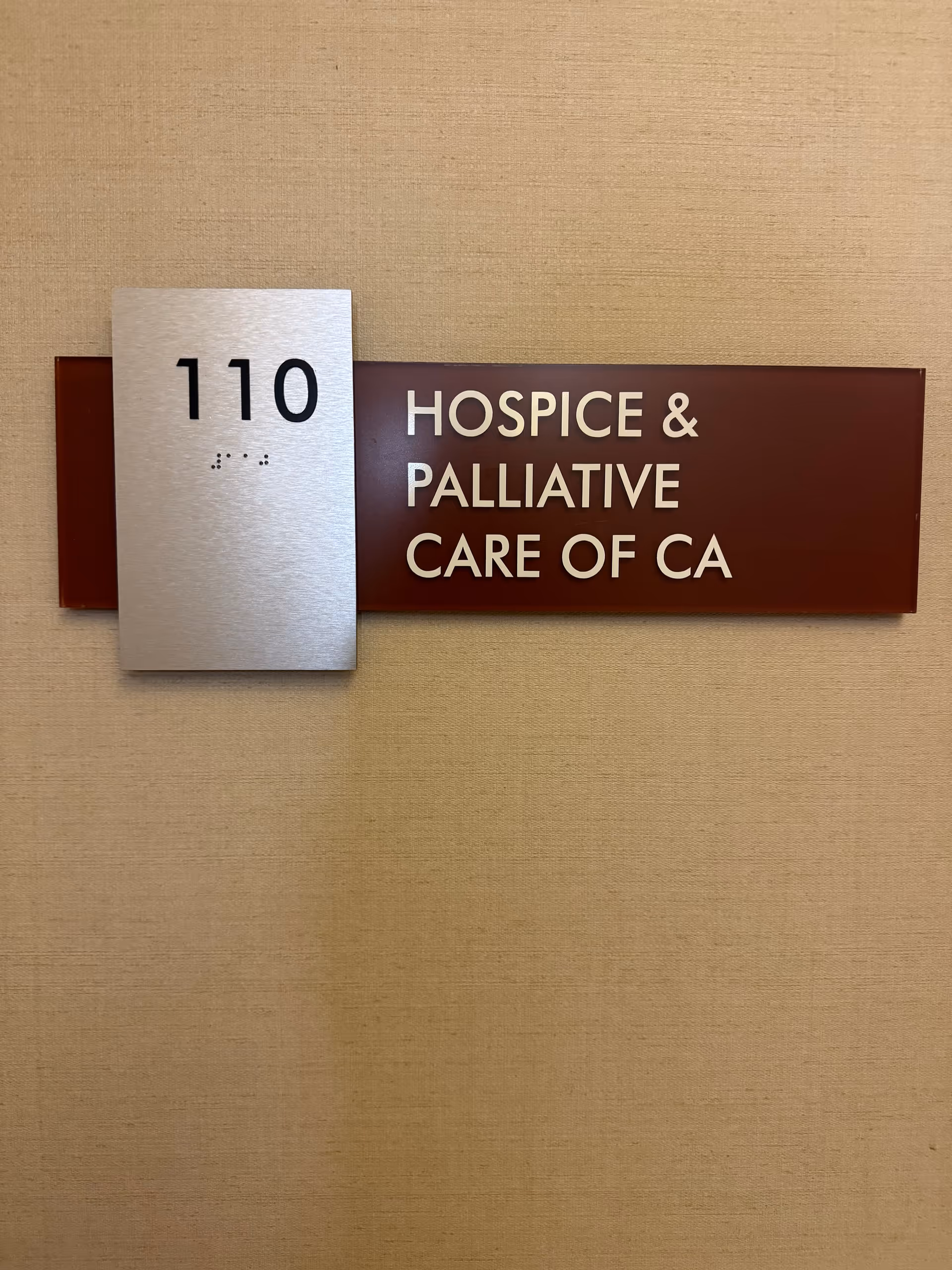 Wall-mounted sign showing room 110 and Hospice & Palliative Care of CA.