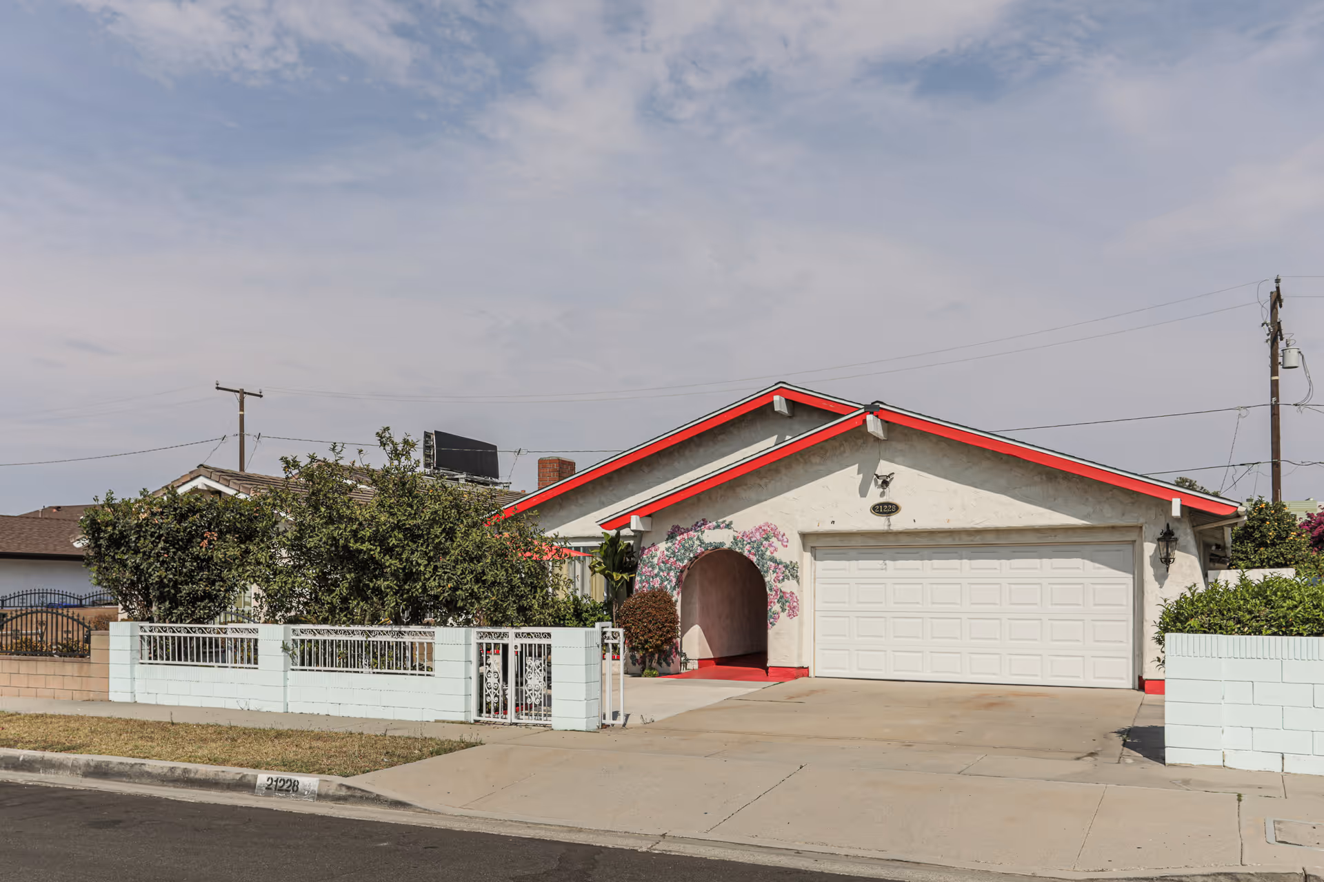 Front exterior of a single-story senior living facility with a white garage and red trim.