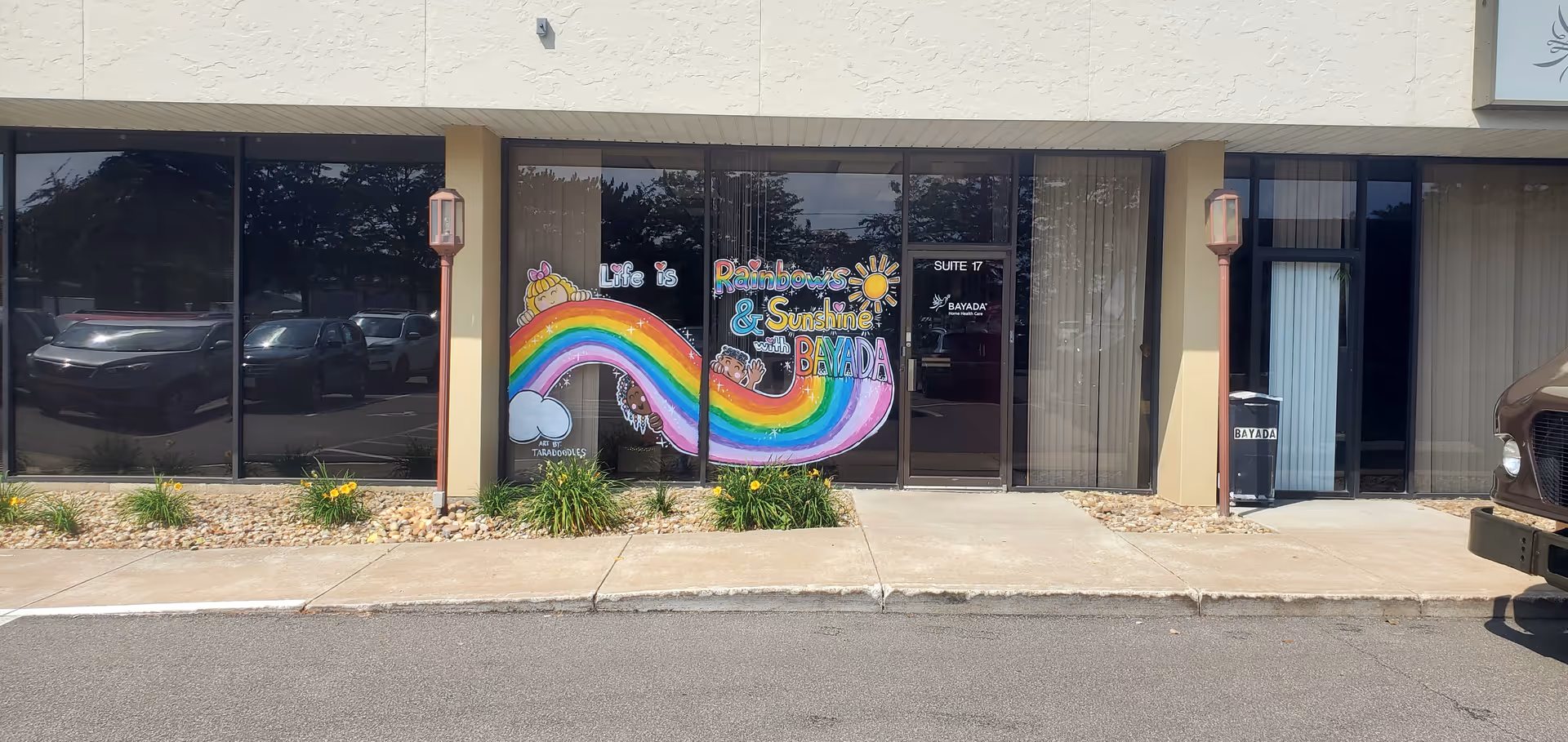 Storefront with large glass windows and a colorful rainbow mural for BAYADA Pediatrics