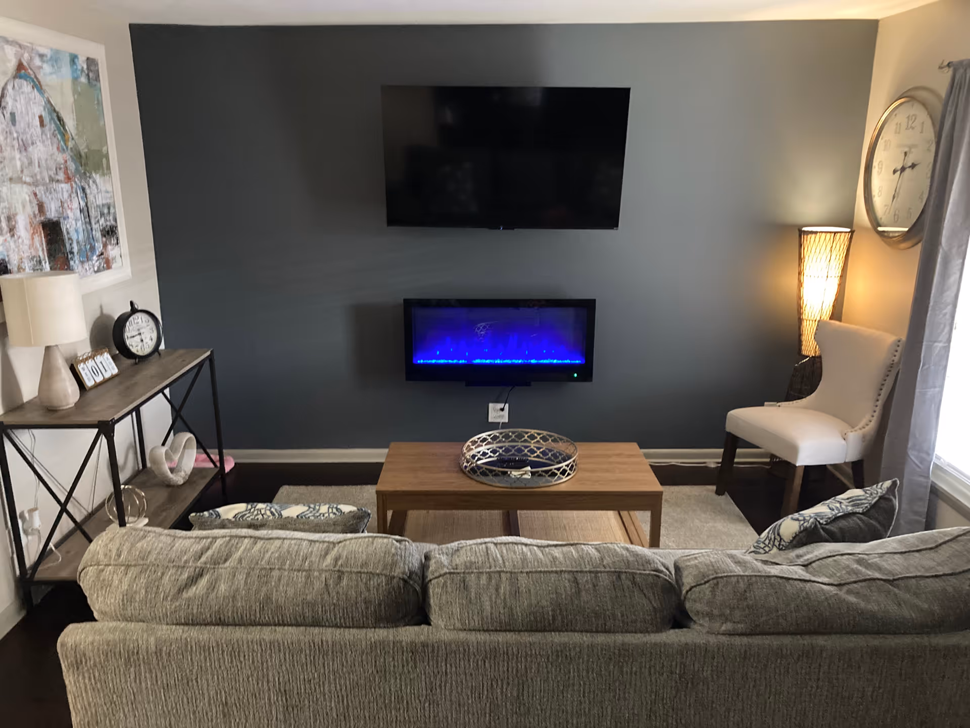 Living room setup with gray sofa, wall-mounted TV, and electric fireplace.