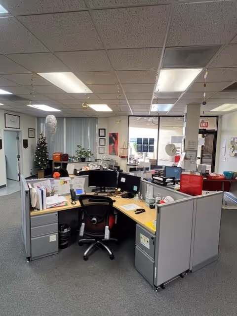 Open-plan office area with cubicles, computers, and a holiday tree inside a BAYADA facility.