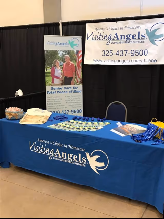 Indoor expo booth for Visiting Angels with blue table cover and banners.