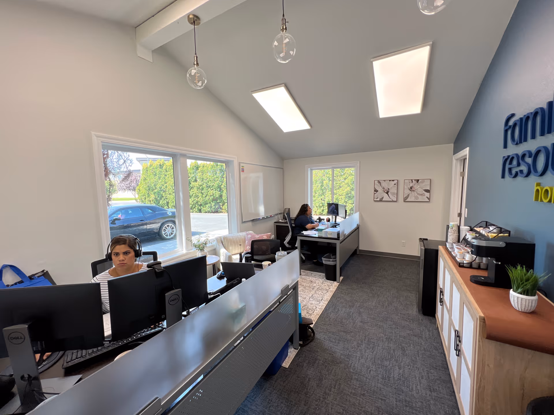 Interior office reception with staff at computers, windows, and a branded blue wall.