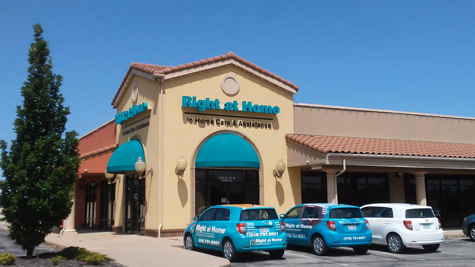 Exterior view of a Right at Home building with teal awnings and parked cars.
