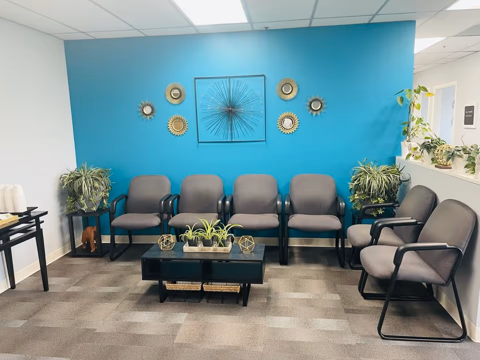 Interior waiting area with blue feature wall, chairs, and greenery.