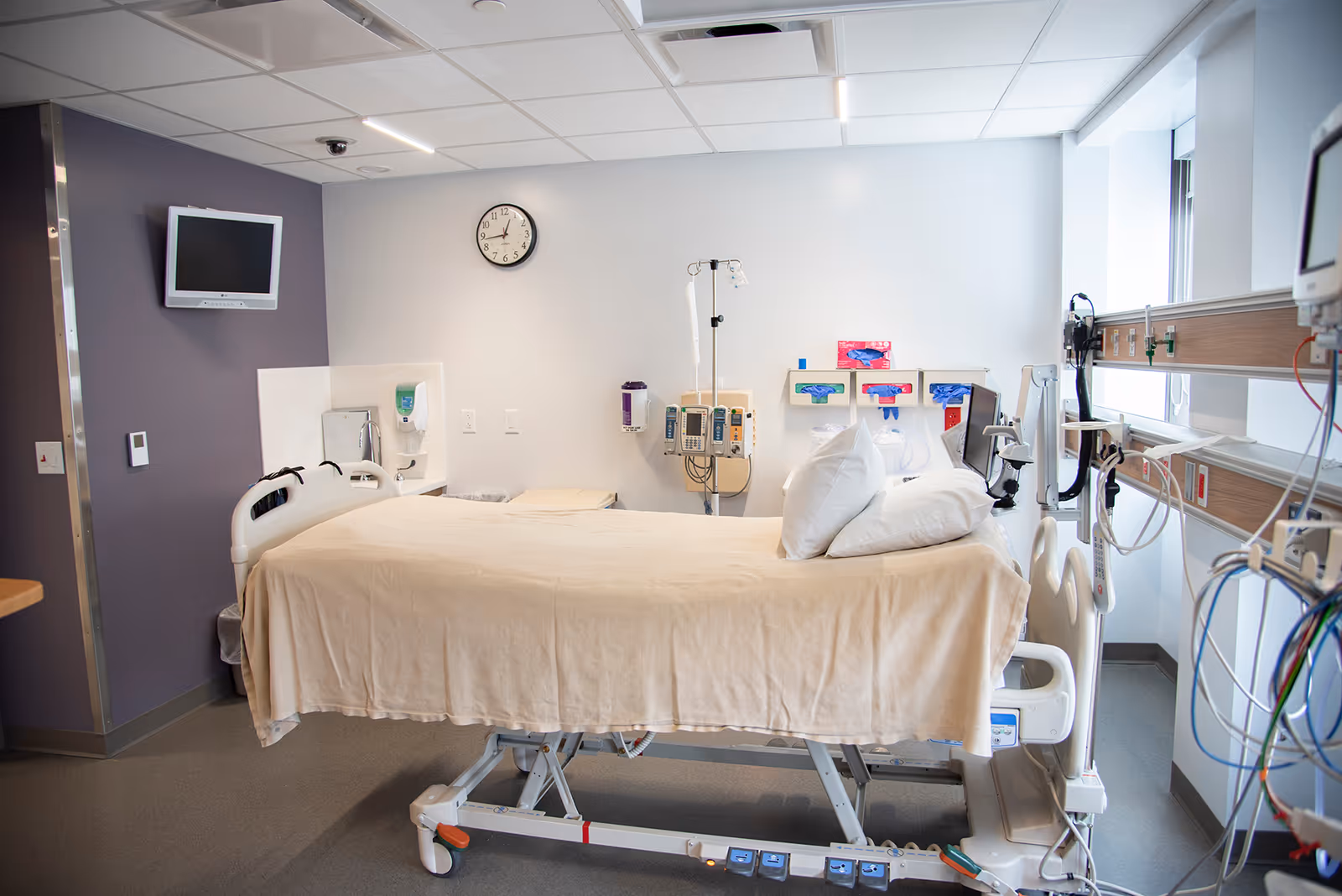 A hospital patient bed in a clinical room with medical equipment.