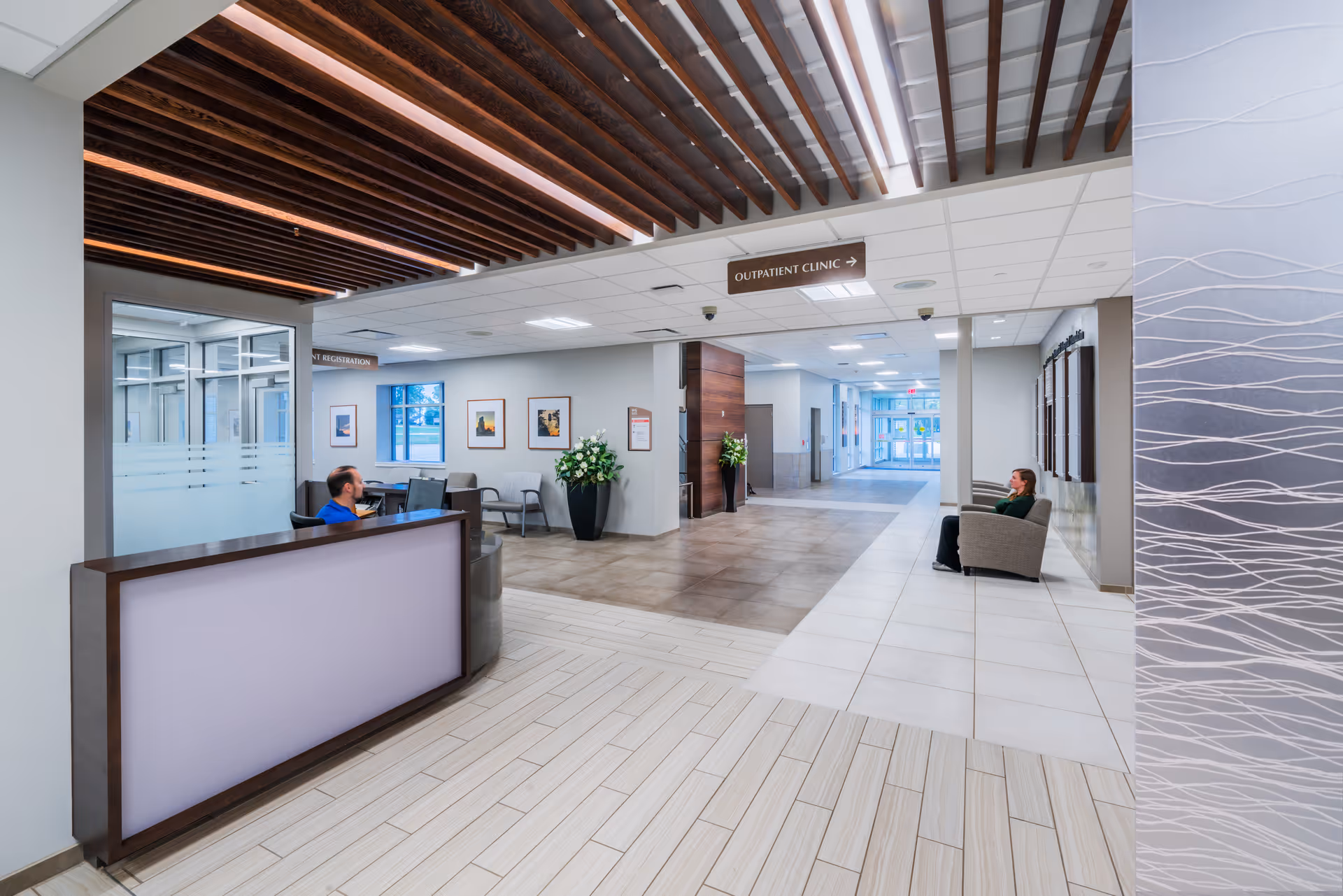 Hospital lobby interior with reception desk and seated visitors along a corridor