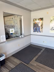 Reception area with window, welcome sign, and wall posters in a senior living lobby.