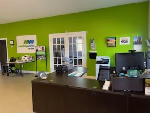 Bright green-walled reception area with a dark front desk and MobilityWorks signage.