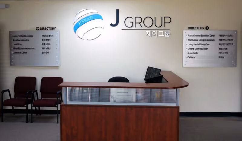 Reception area featuring a wooden desk, laptop, chairs, and directory signs.
