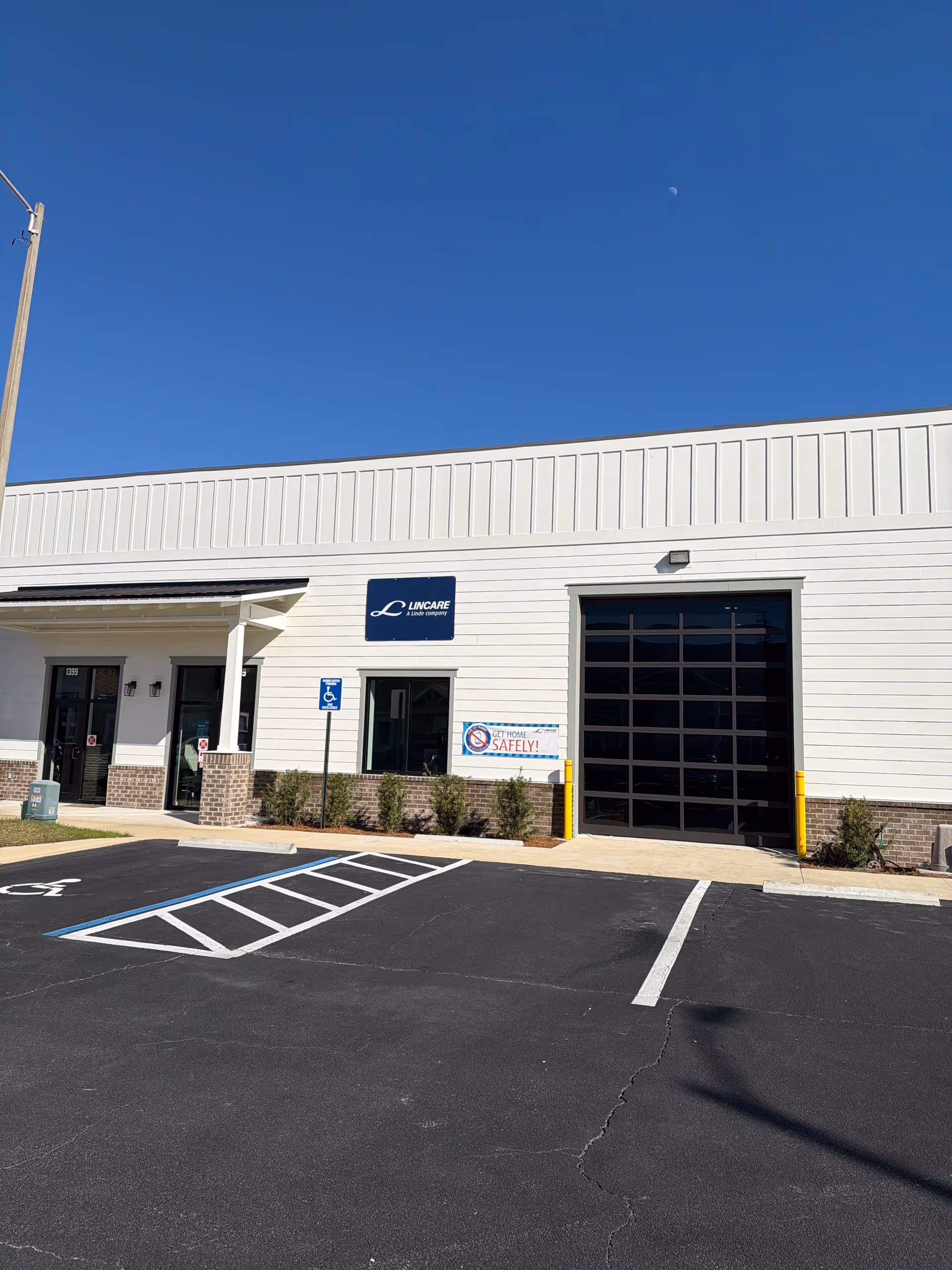 Exterior view of a LINCARE facility with a parking lot and large entry doors.