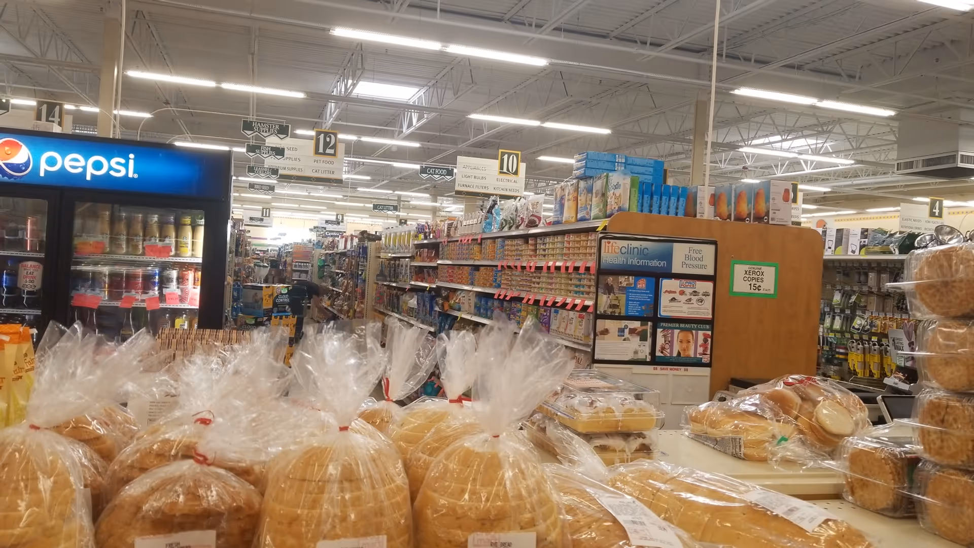 Inside a Discount Drug Mart store, shelves display bread loaves, beverages, and grocery items.