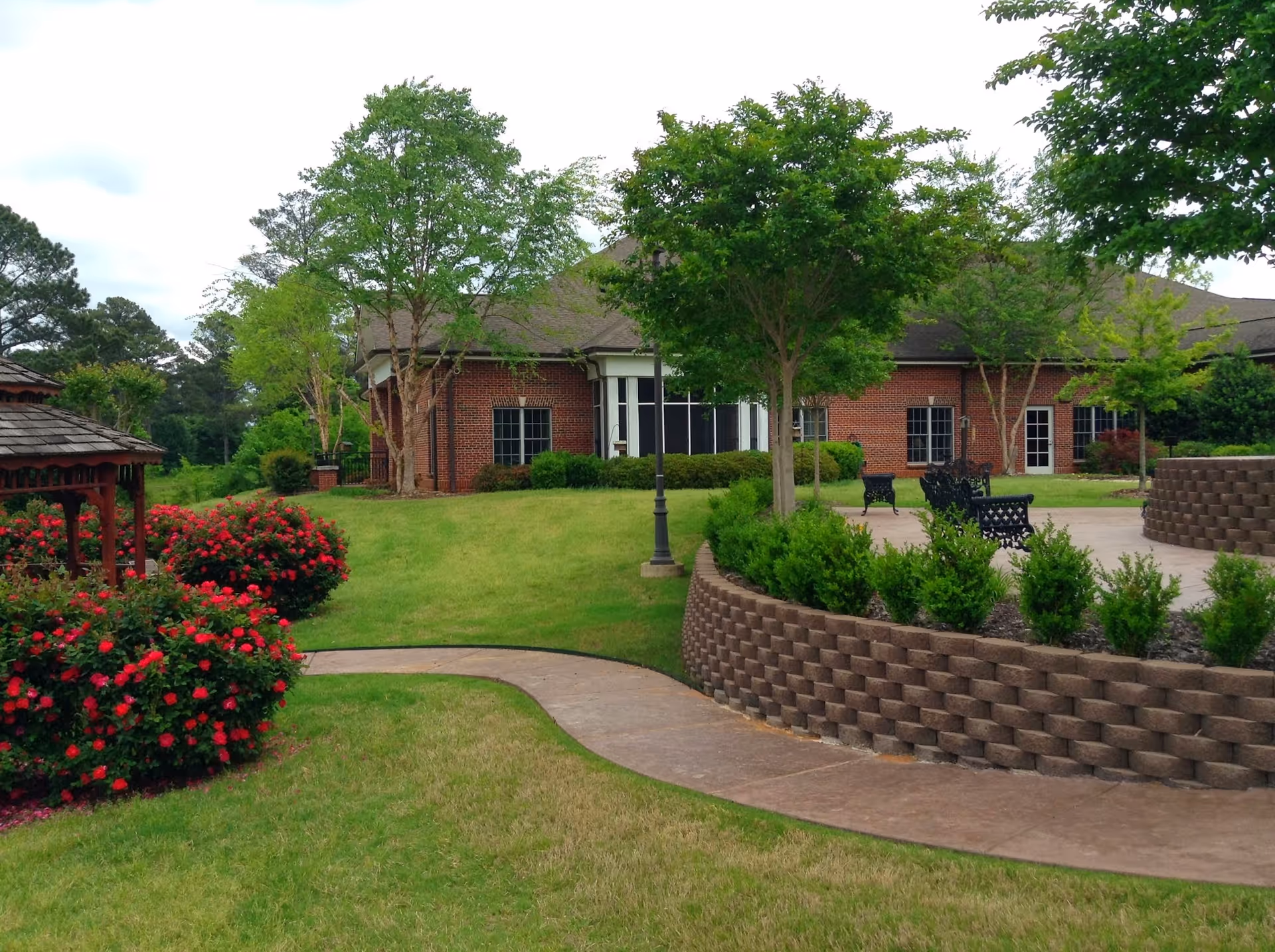 Hospice of West Alabama outdoor courtyard with brick building, greenery, and benches.