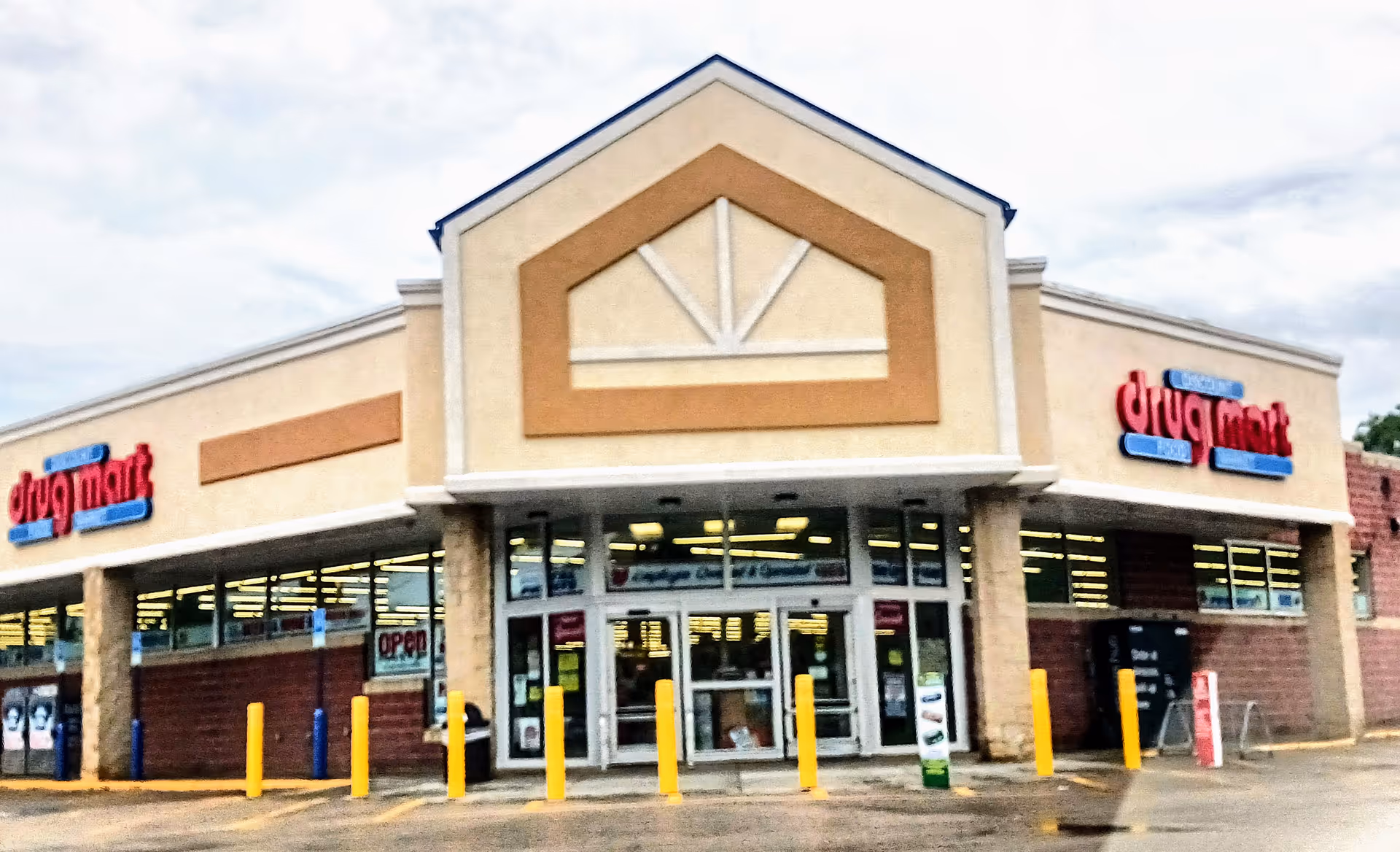 Exterior view of Discount Drug Mart storefront with glass doors and a parking lot.
