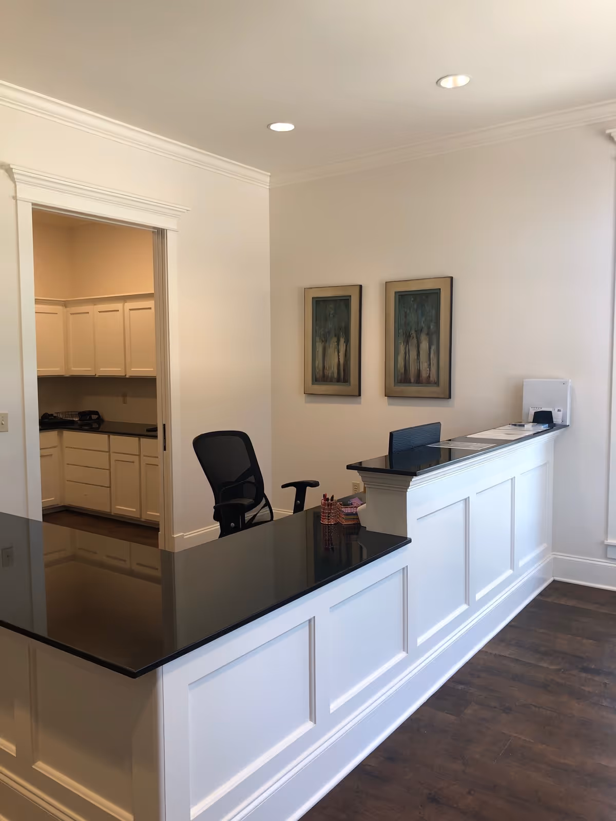 Reception desk with black countertop in a bright white interior lobby.