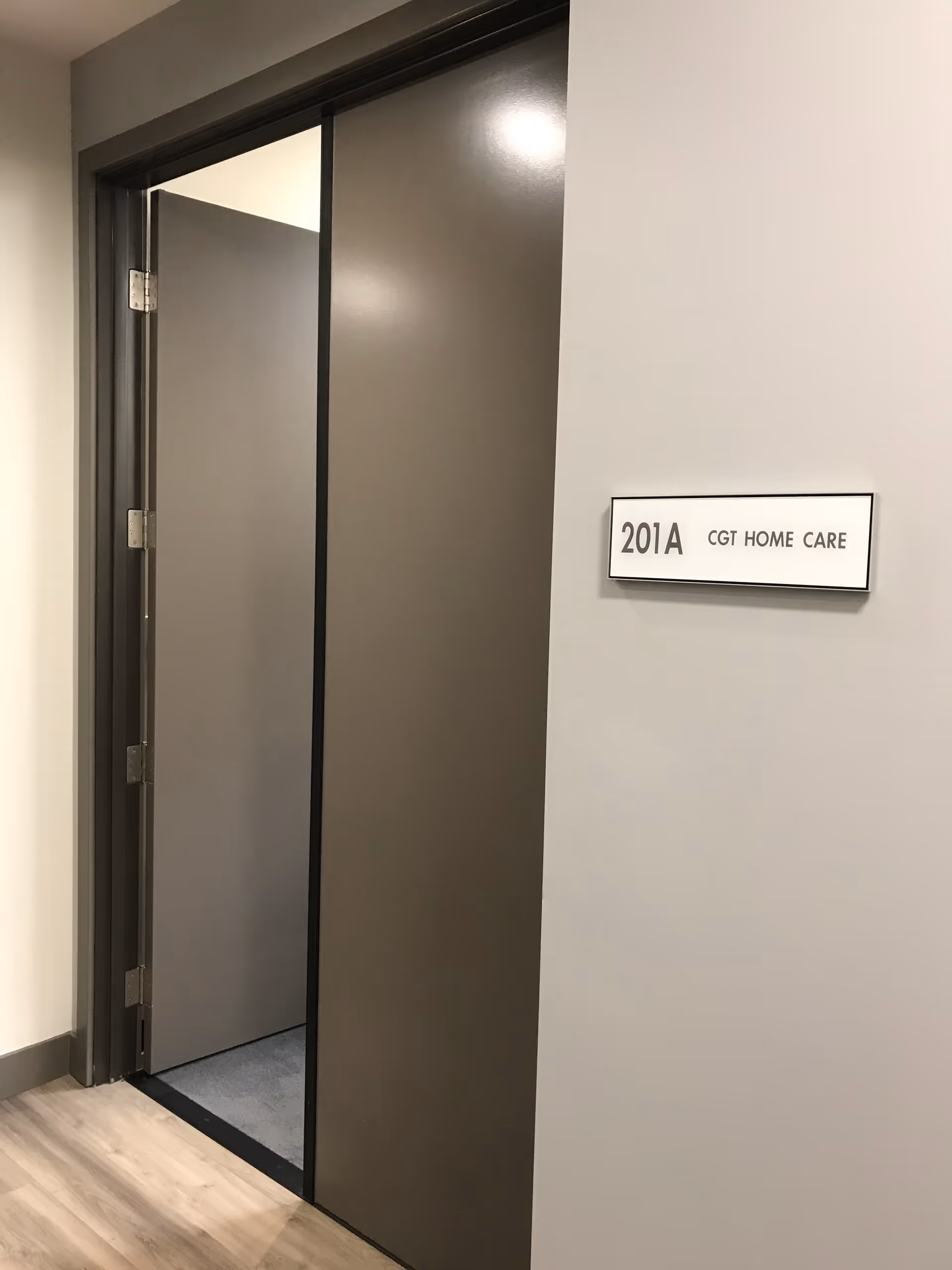 Open elevator doors along a hallway with a 201A CGT Home Care sign.