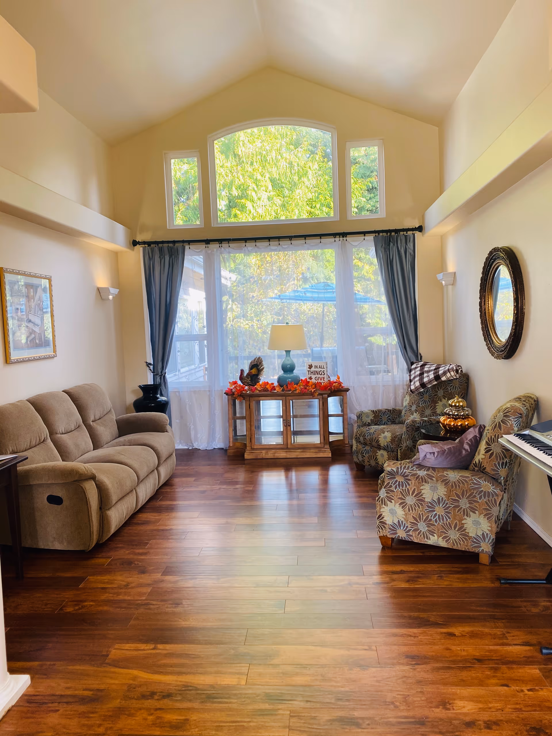 Bright living room with beige sofa, patterned chairs, and a large window.