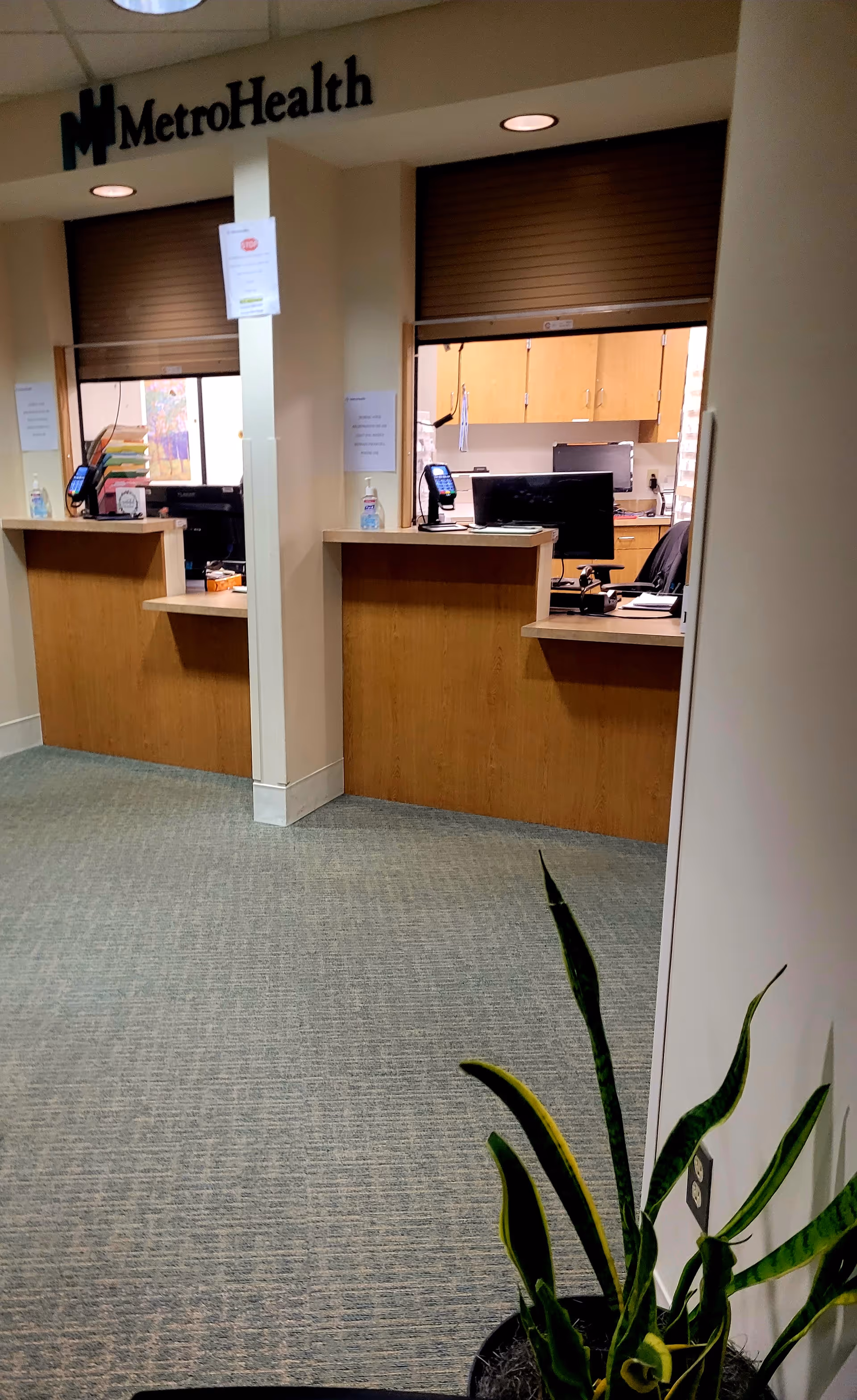 Interior reception area with two wooden front desks and MetroHealth signage.