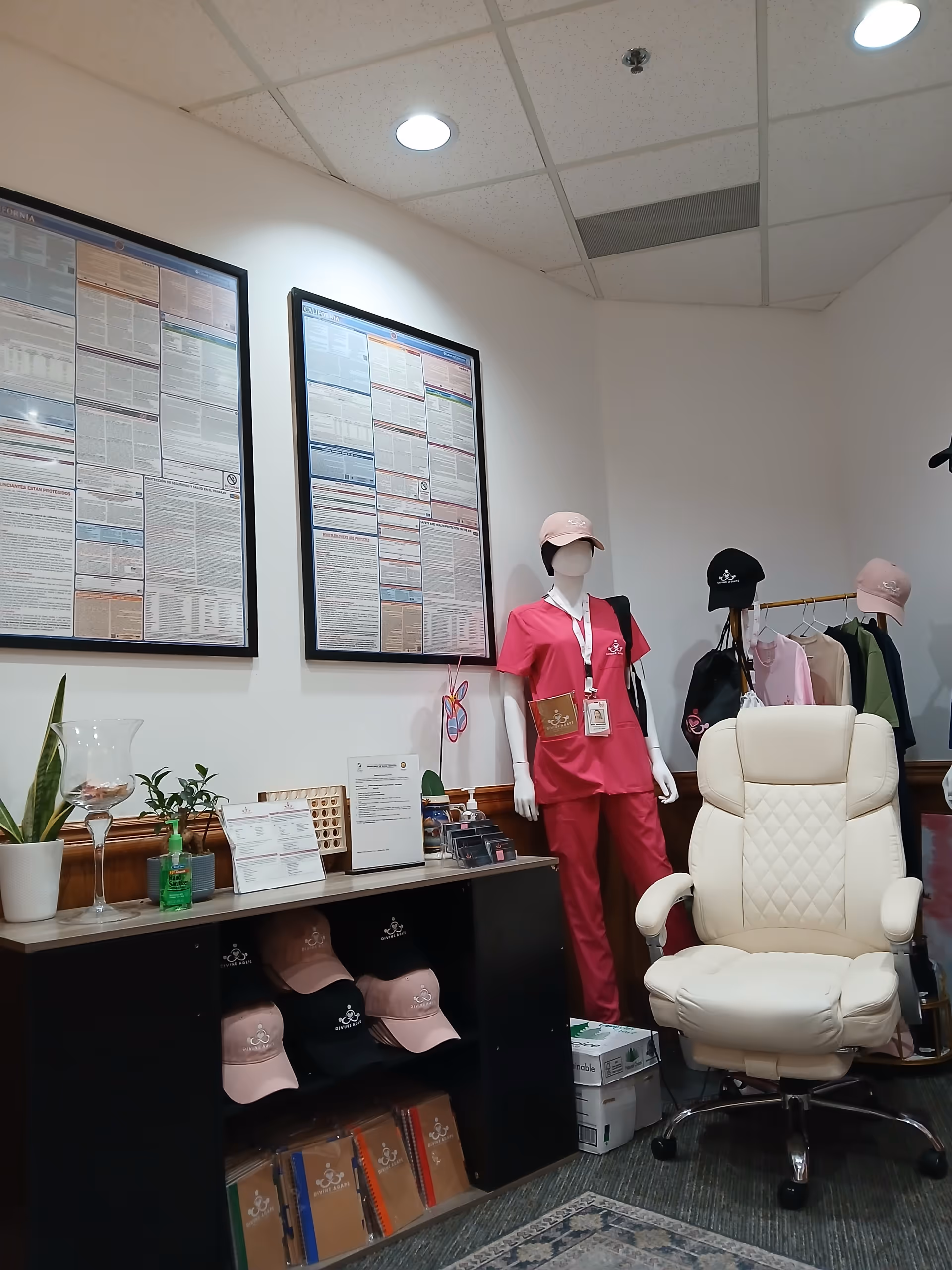 Interior showroom with mannequins in pink medical scrubs, hats, a white chair, and wall posters.