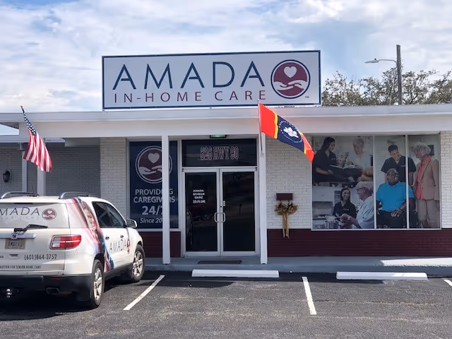 Front view of Amada In-Home Care storefront with a parked branded car.