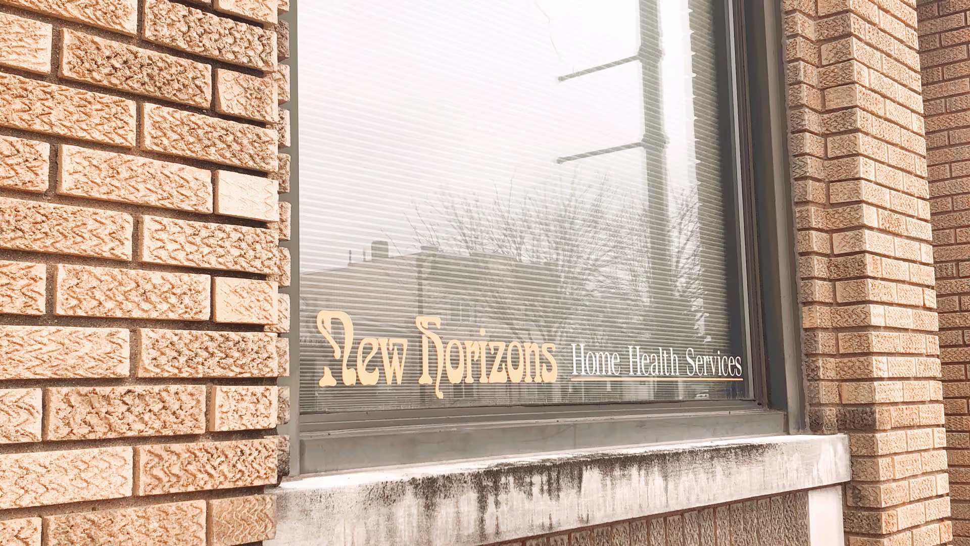 Brick building exterior with window sign: New Horizons Home Health Services.