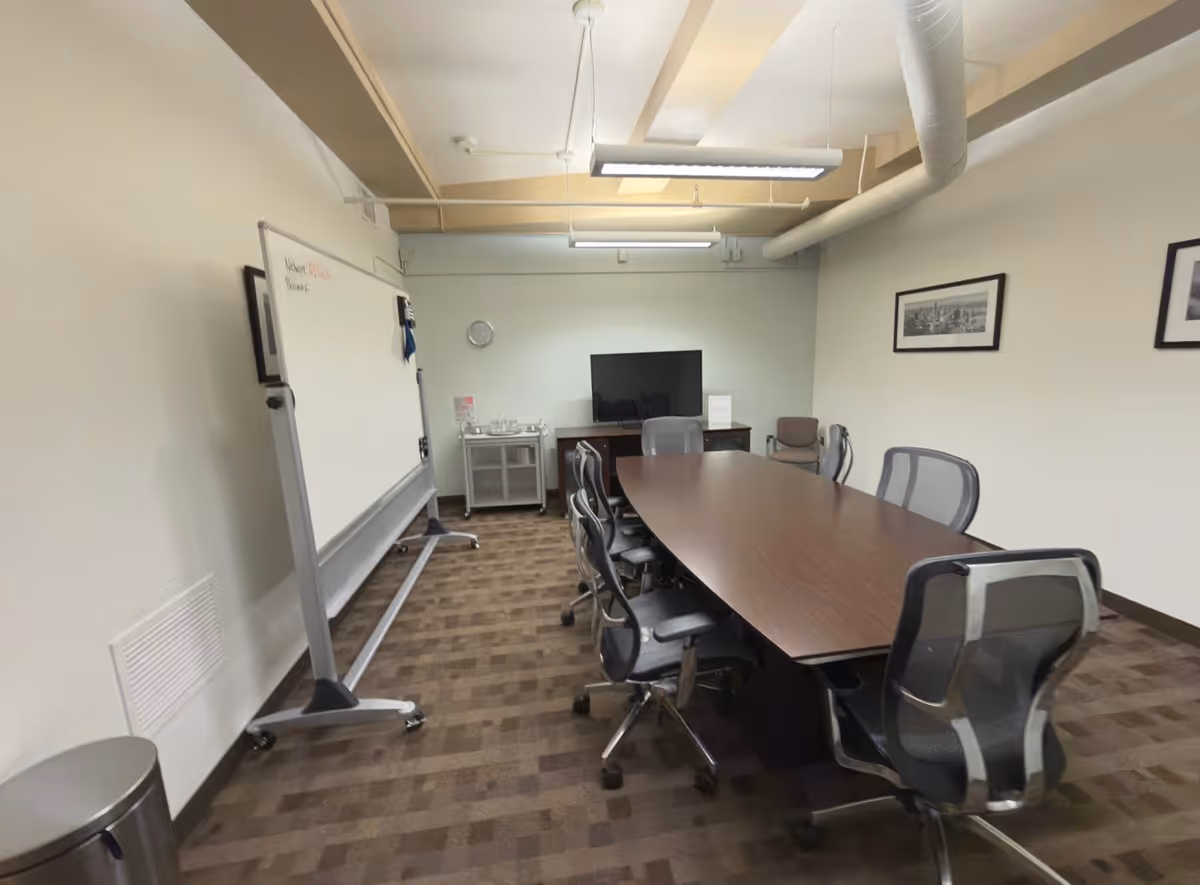 Long conference table with rolling chairs in a meeting room.