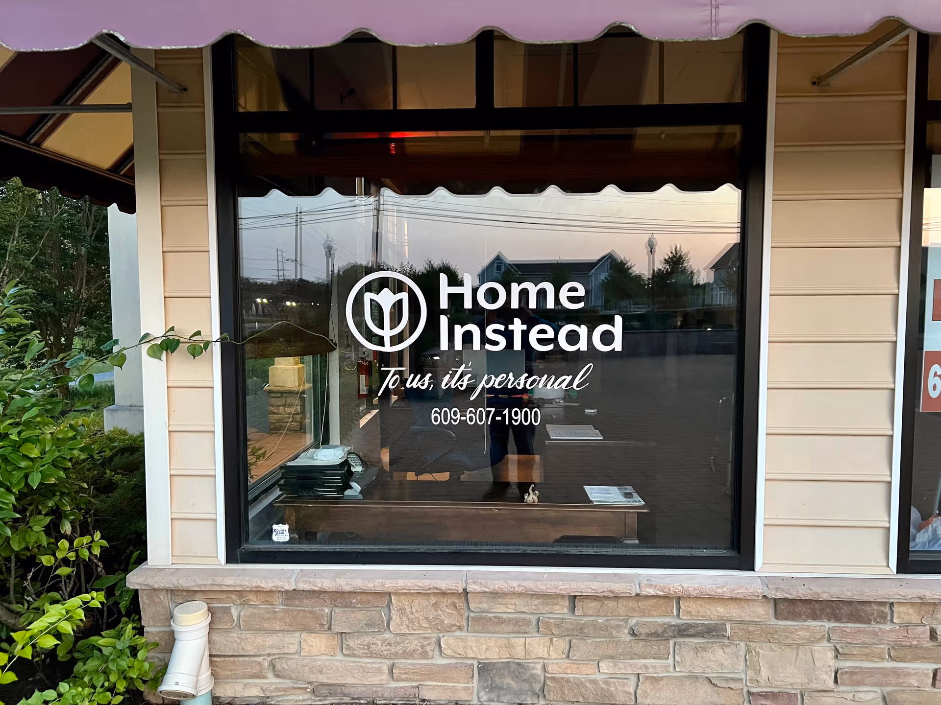 Front of a Home Instead facility with glass window signage and logo.