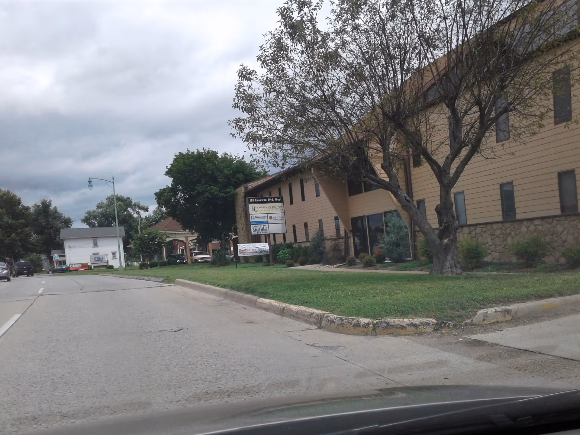 Street view of CenterWell Home Health facility with trees, sign, and tan building facade.