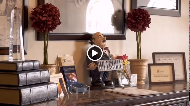 Interior lobby front desk with welcome sign, statue, books, certificates, and plants.