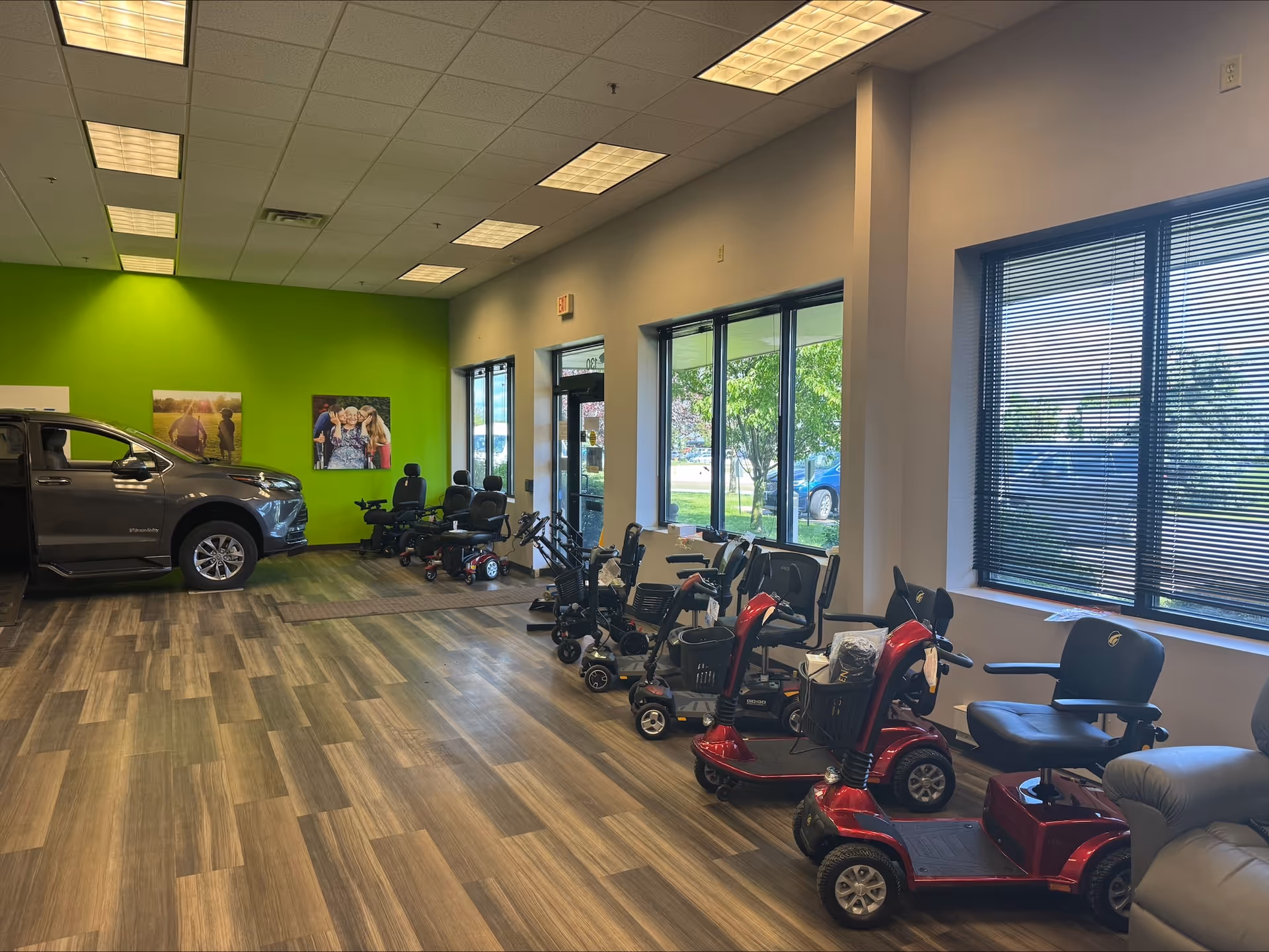 Interior MobilityWorks showroom with multiple scooters and assistive devices, plus a parked car.