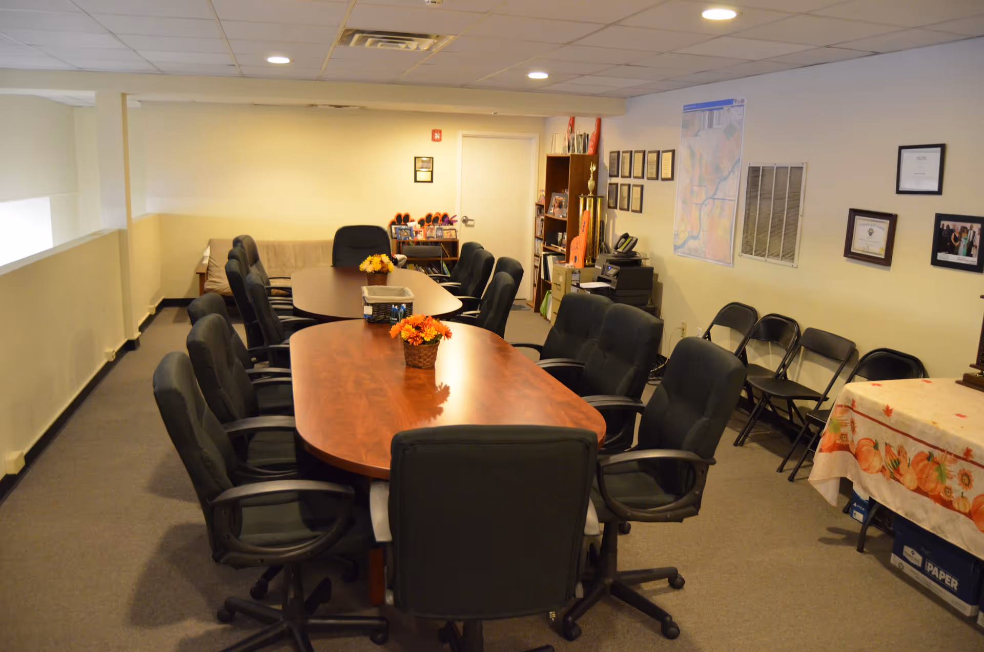Long wooden conference table surrounded by black chairs in a bright meeting room.