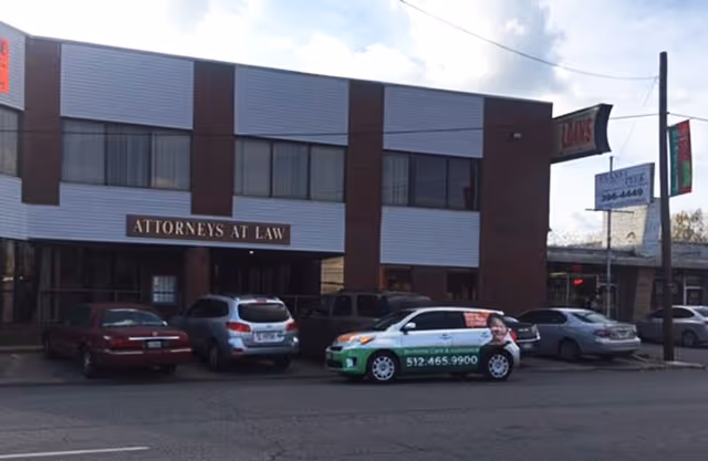 Two-story brick-and-white building with 'Attorneys at Law' sign and parked cars.