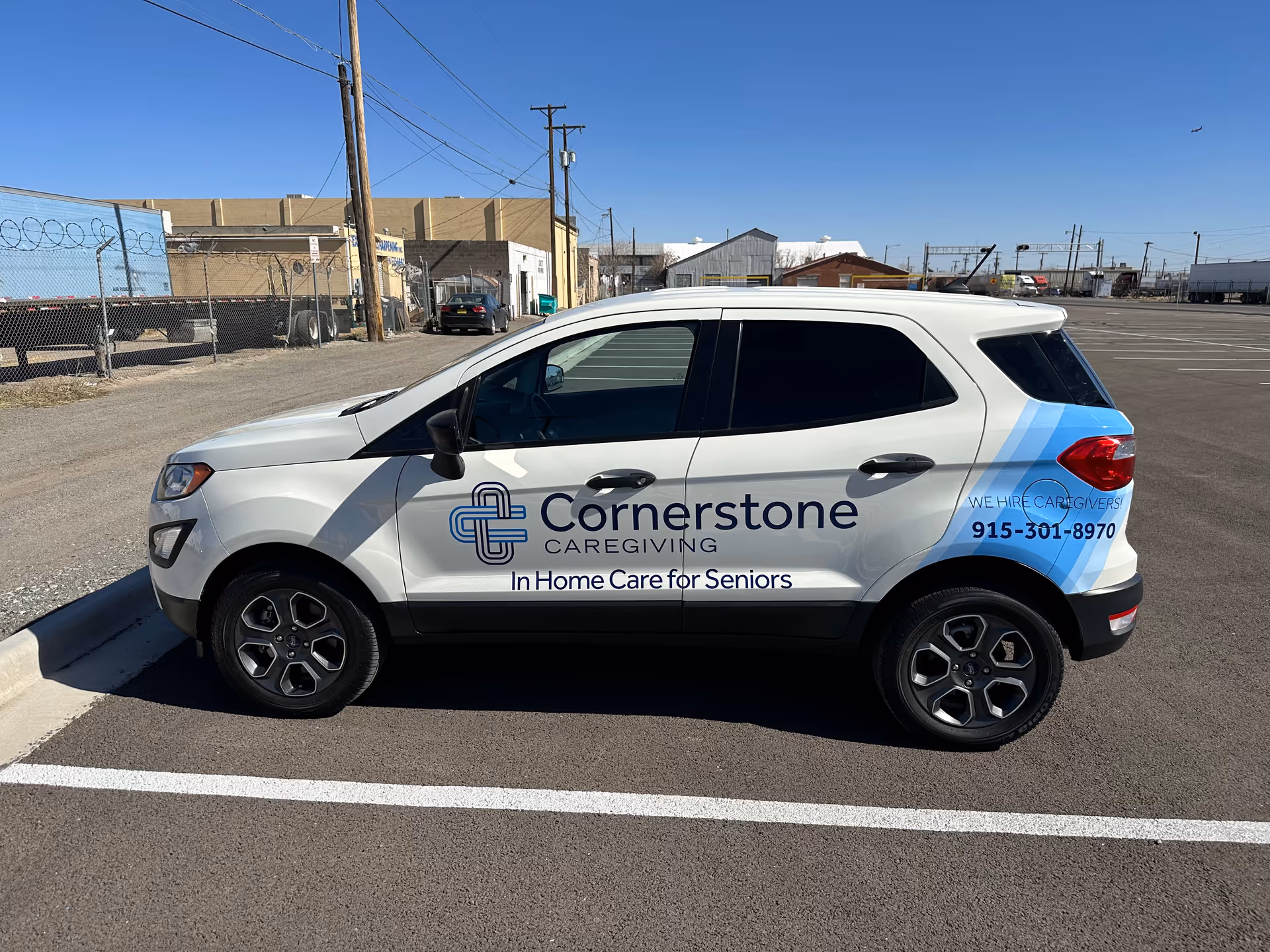 Cornerstone Caregiving vehicle parked in an empty lot beside industrial buildings.
