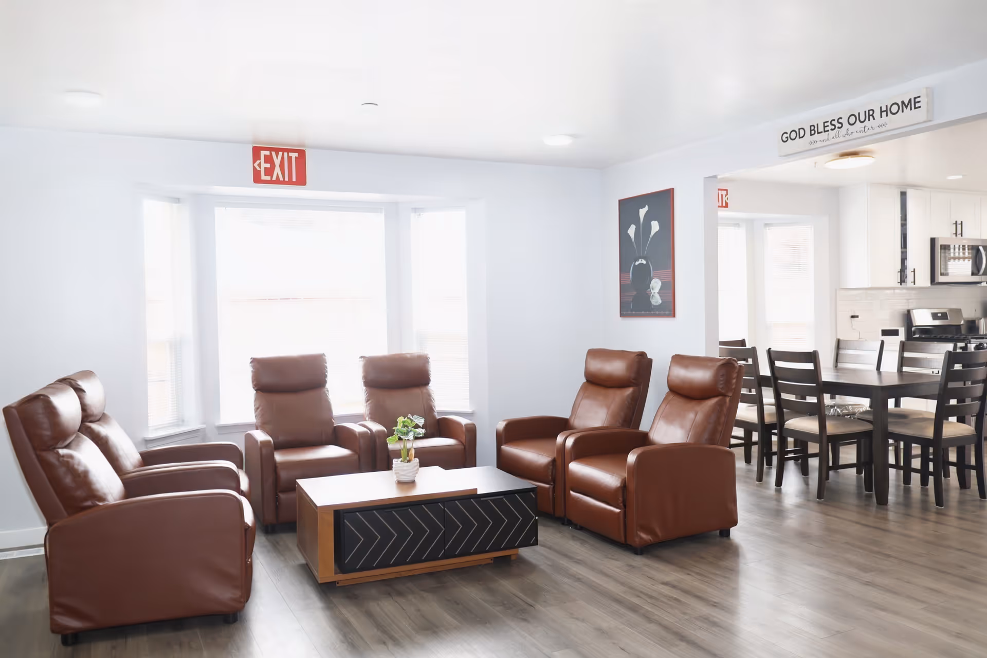 Lobby-style living room with brown leather recliners, coffee table, and an open kitchen/dining area.
