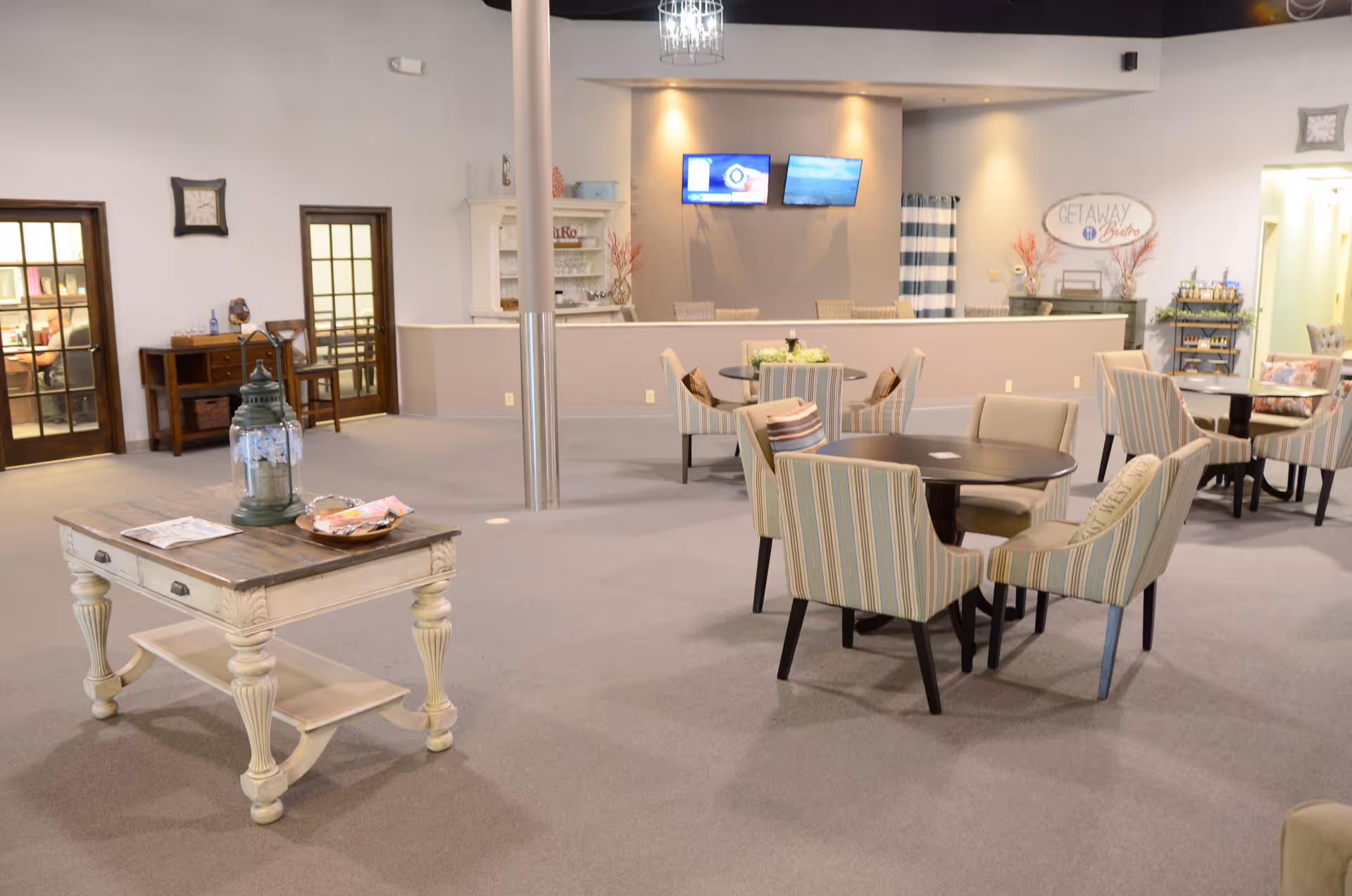 Wide, well-lit lounge area with round tables, striped chairs, and a front desk.