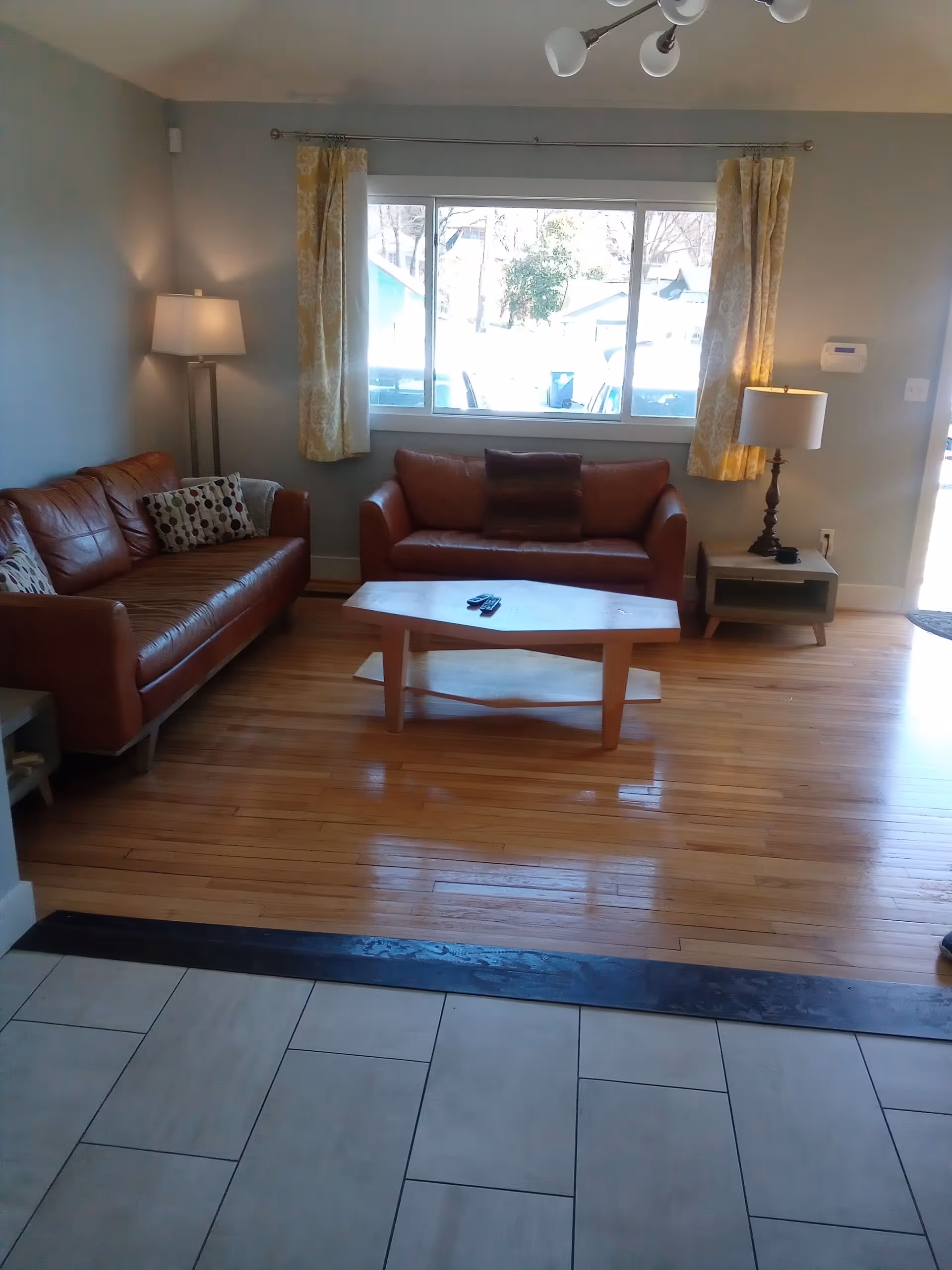 Cozy living room with brown leather sofas, wooden coffee table, and a large window.