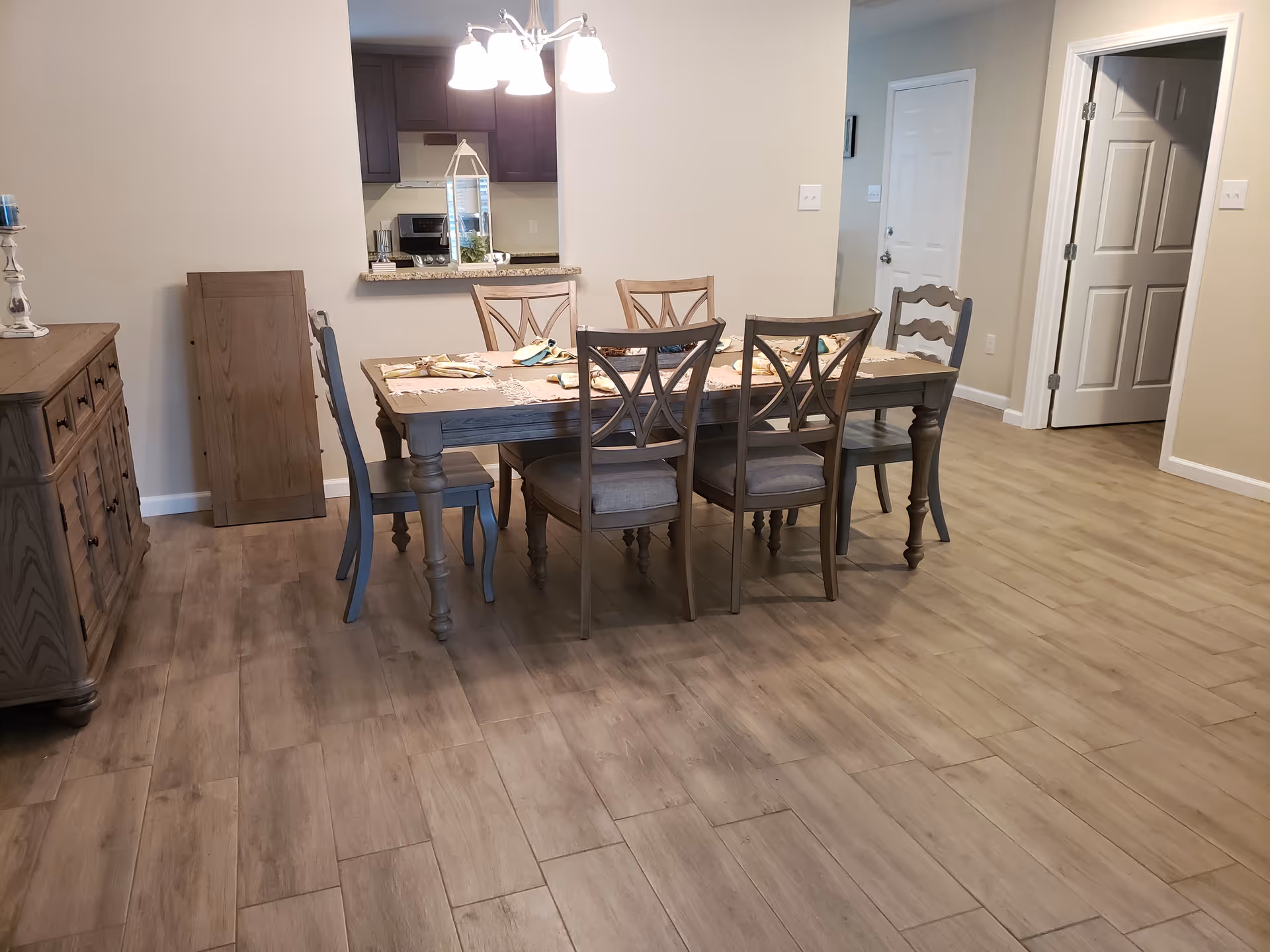 A dining area with a long wooden table, chairs, and an open kitchen pass-through.