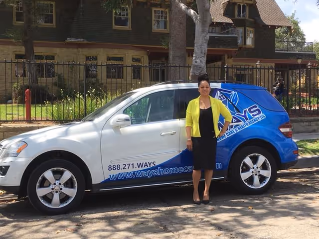 A staff member standing beside a Ways Home Care van parked outside a building.