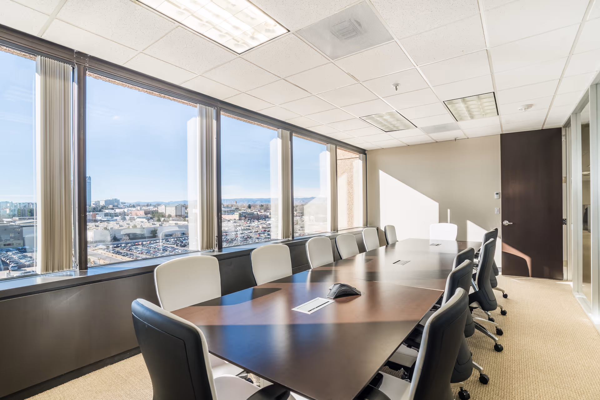 Bright conference room with a long wooden table and panoramic window view.