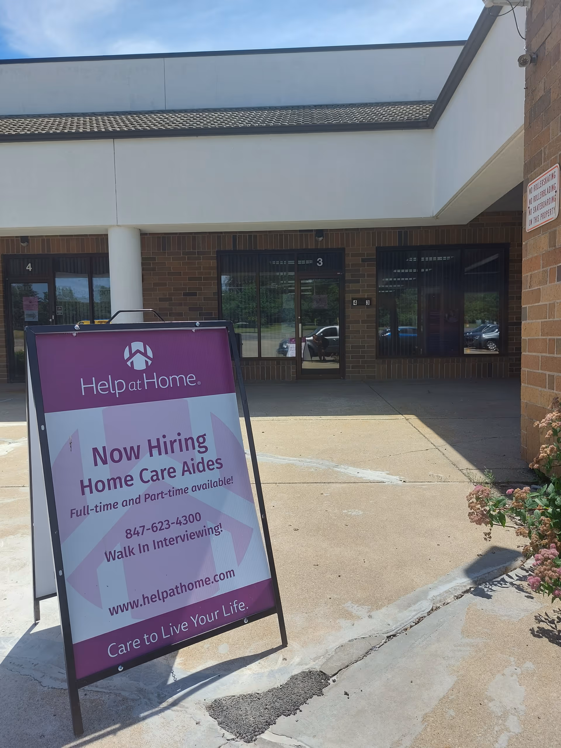 Exterior of Help at Home building with a purple sign advertising hiring outside