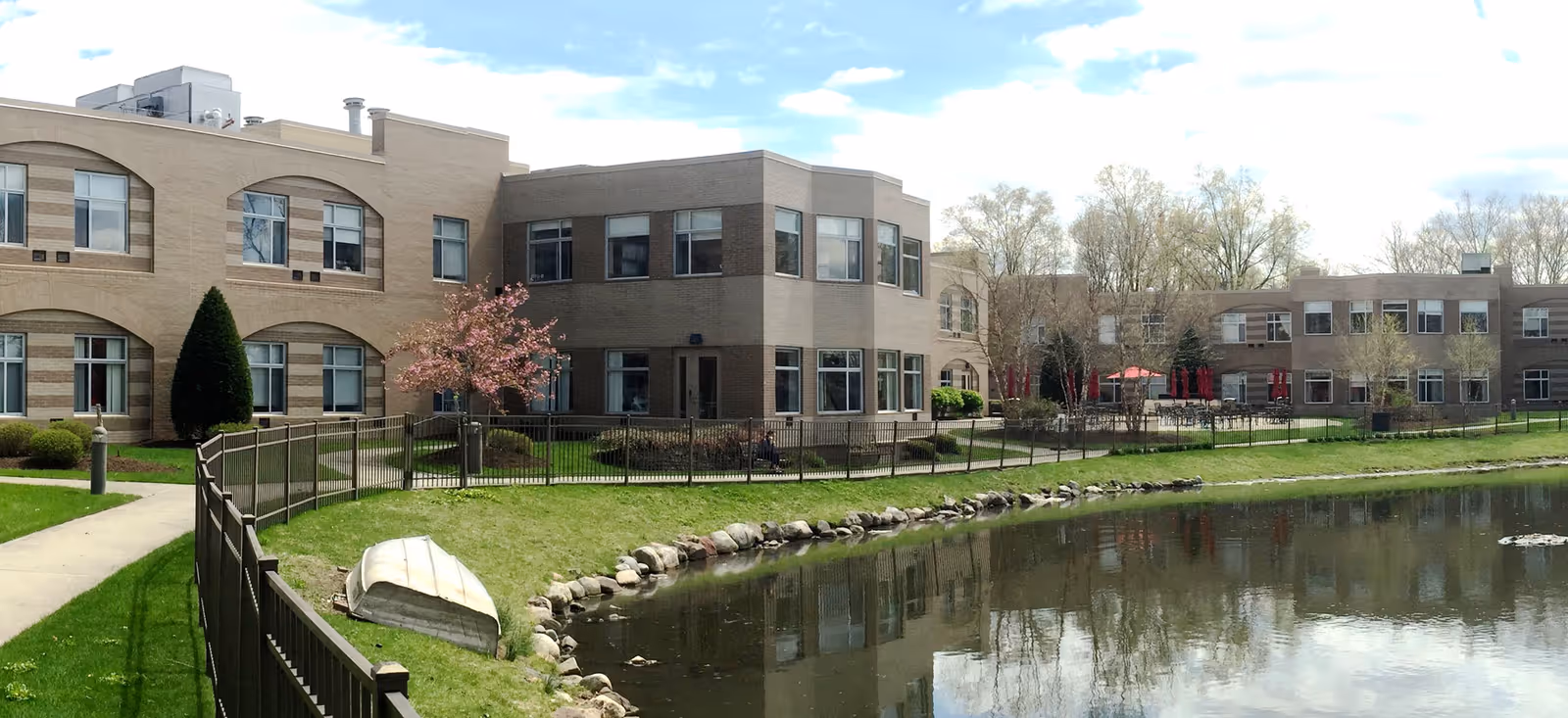 Exterior view of a Jewish Home Family senior living campus beside a pond.