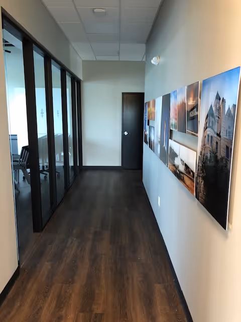 Interior hallway in a senior living facility with glass-walled rooms and wall-mounted artwork.