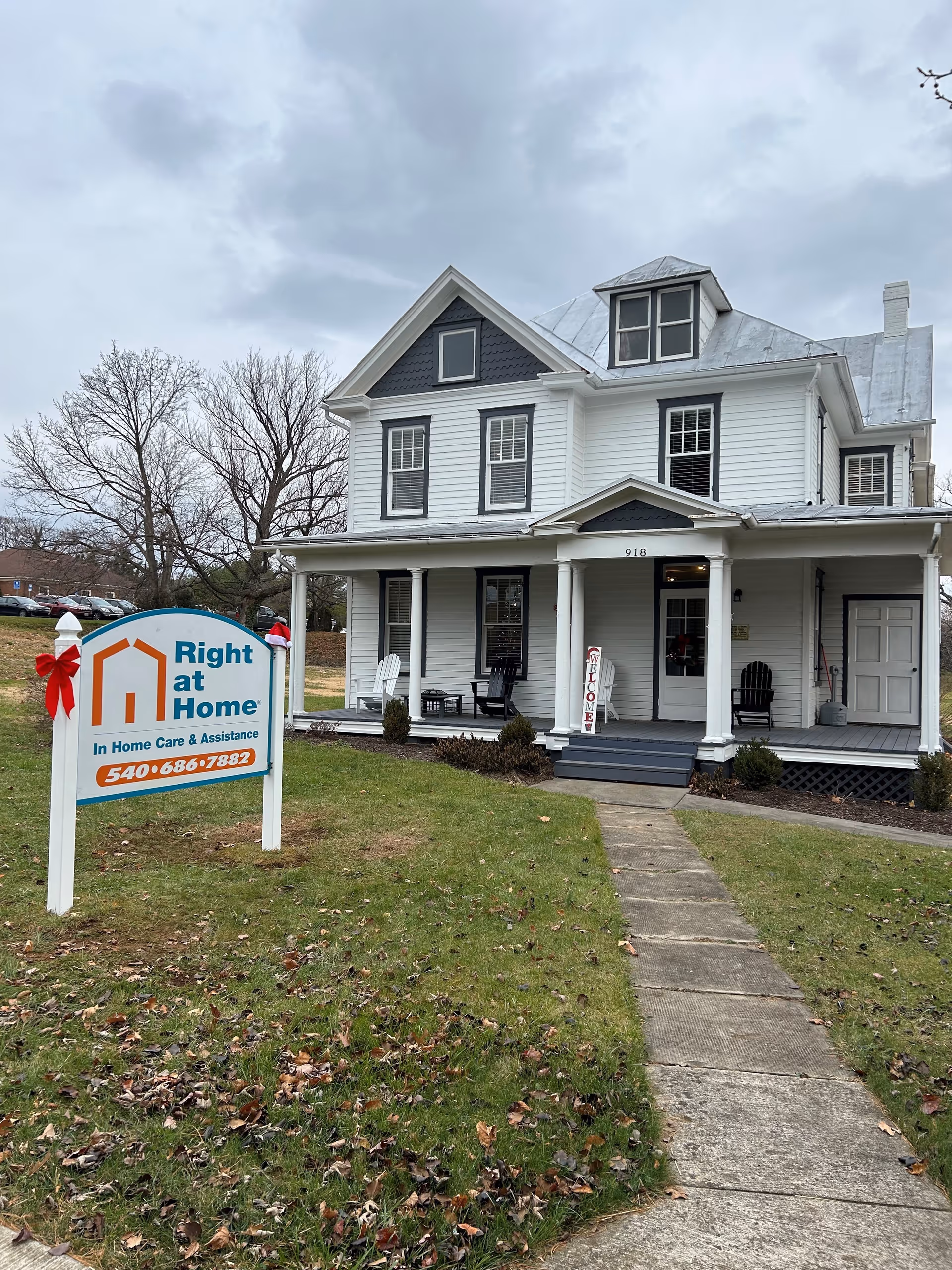 White two-story building with a Right at Home sign and front porch on a grassy lawn.