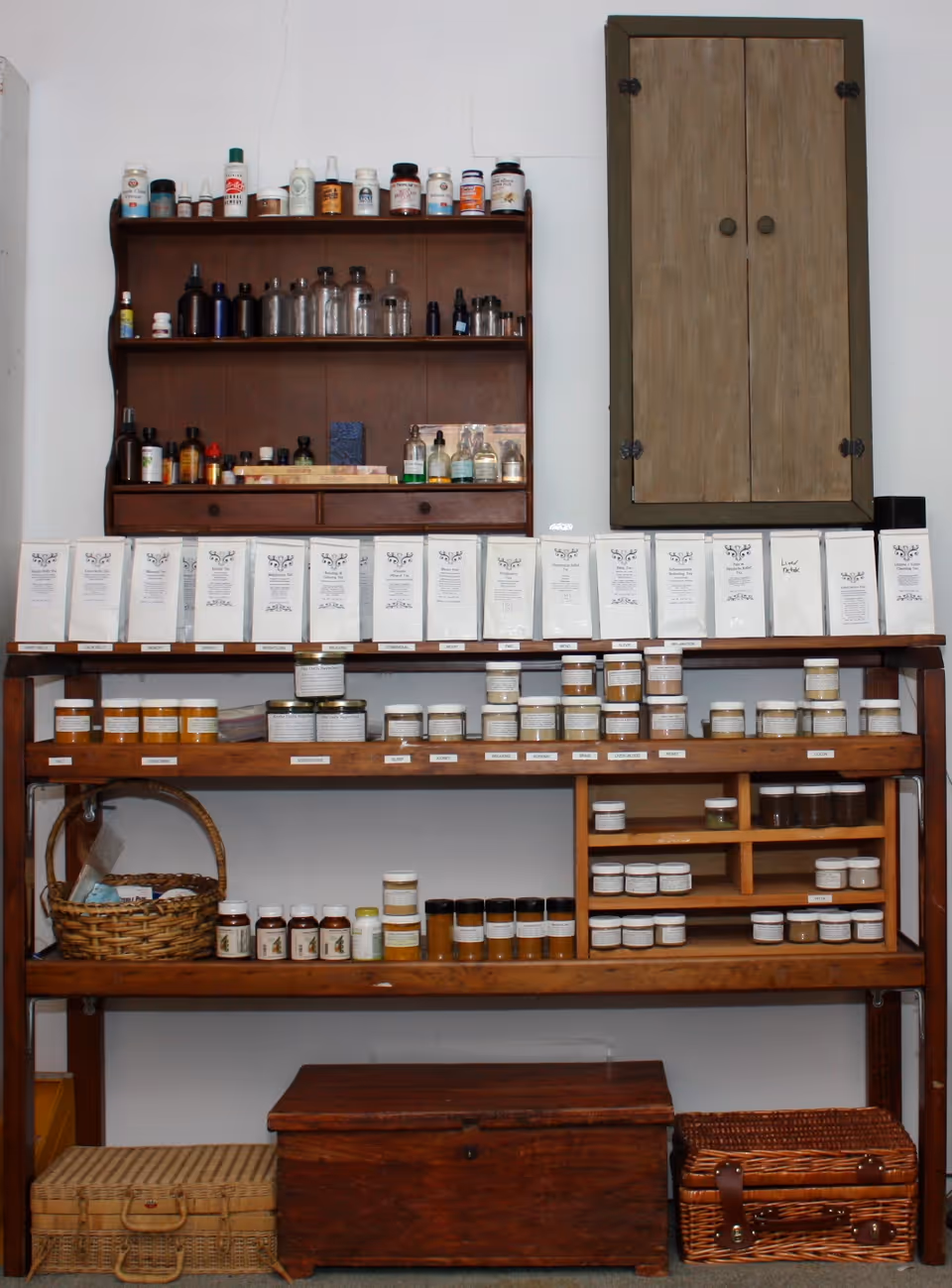 Interior medicine storage with wooden shelves, bottles, jars, and a wall cabinet.