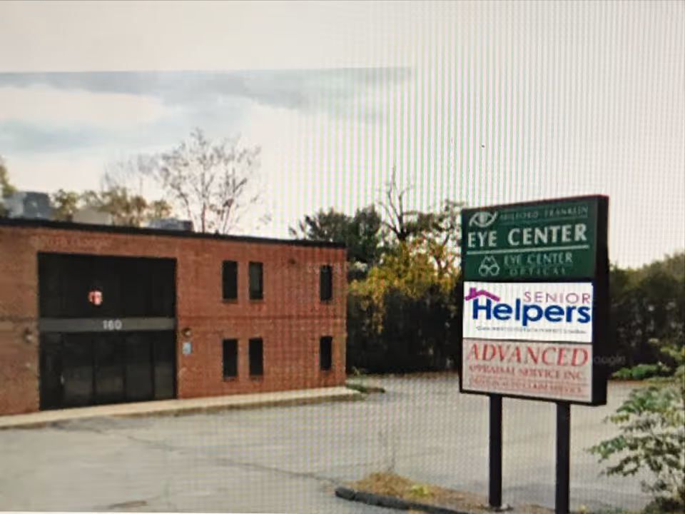 Brick exterior building with a tall signboard advertising Eye Center, Senior Helpers, and Advanced.